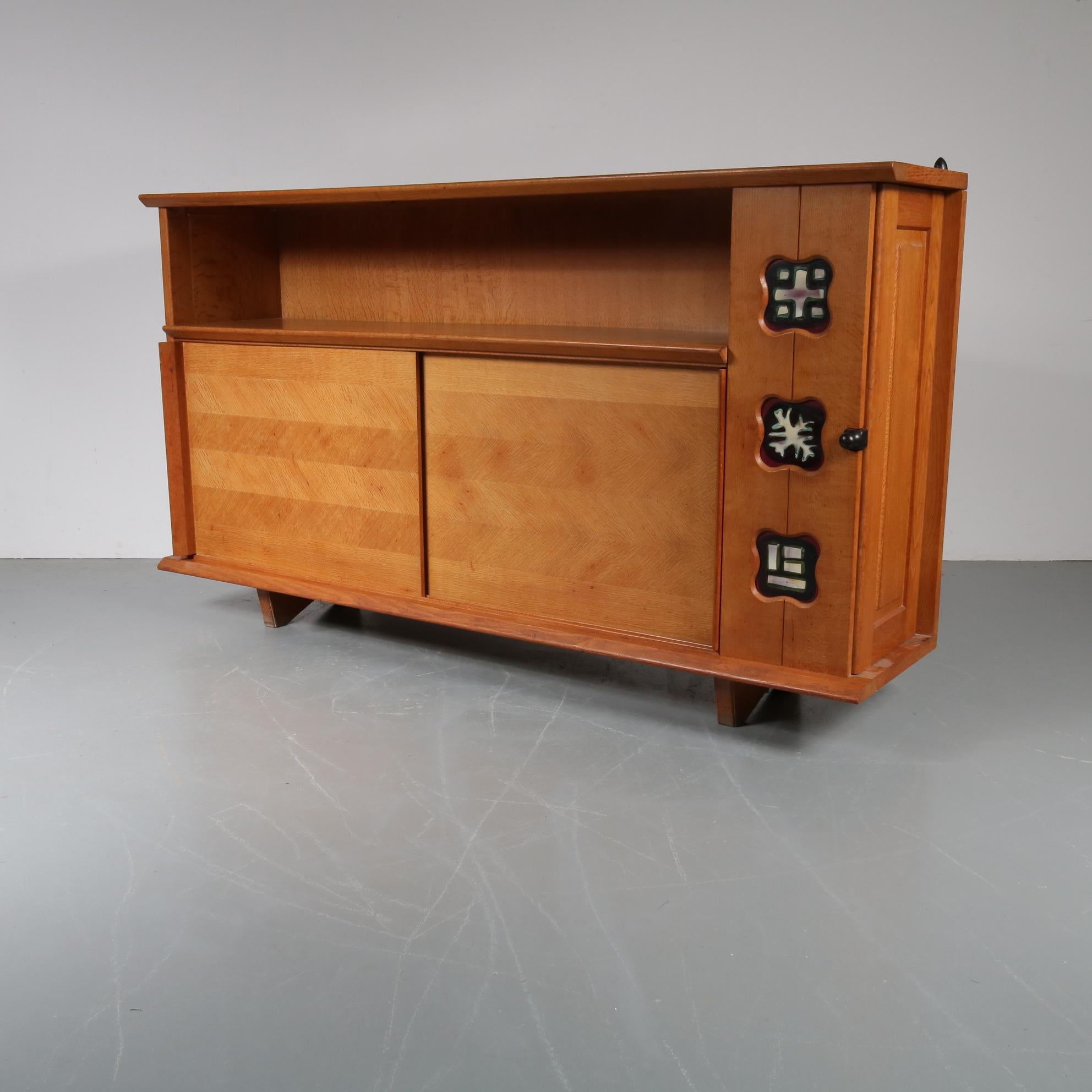 A rare sideboard designed by Guillerme et Chambron, manufactured in France, circa 1950.

Made of high quality oak with a beautiful rustic style and ceramics inlay in the side and top. The ceramics have beautiful, decorative patterns that add a