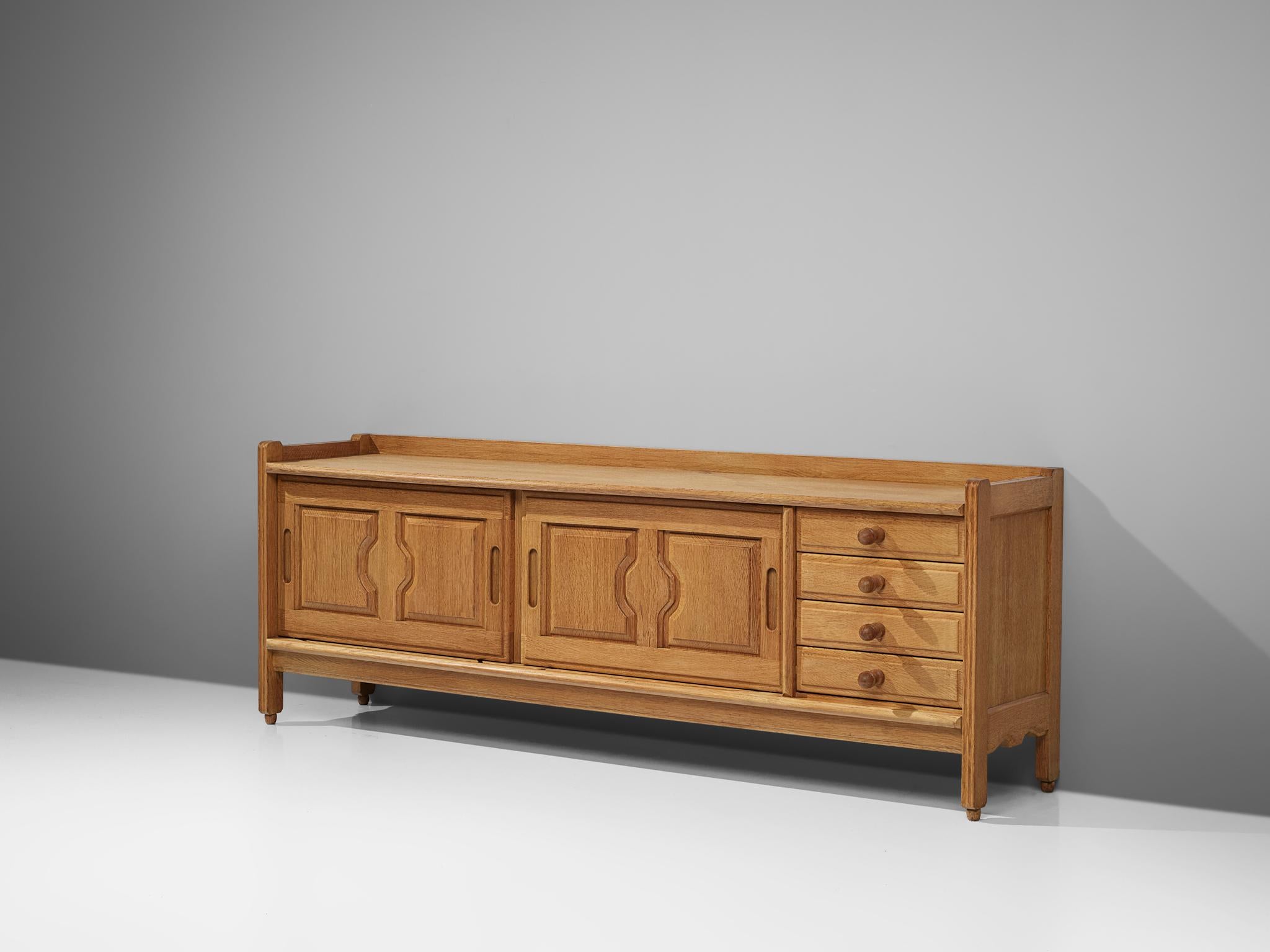Guillerme et Chambron, sideboard, oak, France, 1960s.

Credenza in oak by French designers Guillerme & Chambron. This sideboard is equipped with two sliding-doors and four drawers on the right. The sliding doors are finished with a carved pattern.