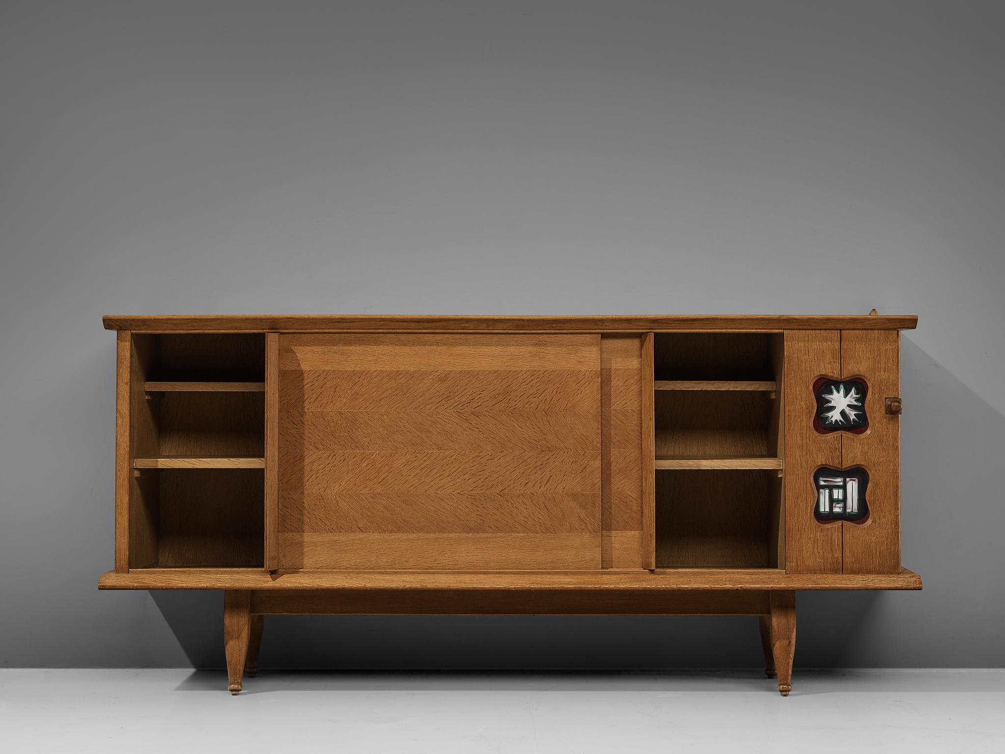 Guillerme et Chambron, credenza, in oak, brass, ceramic tiles, France, 1960s.

Characteristic sideboard in solid oak. This cabinet holds all the characteristics of the French designer duo Jacques Chambron and Robert Guillerme. As many of the