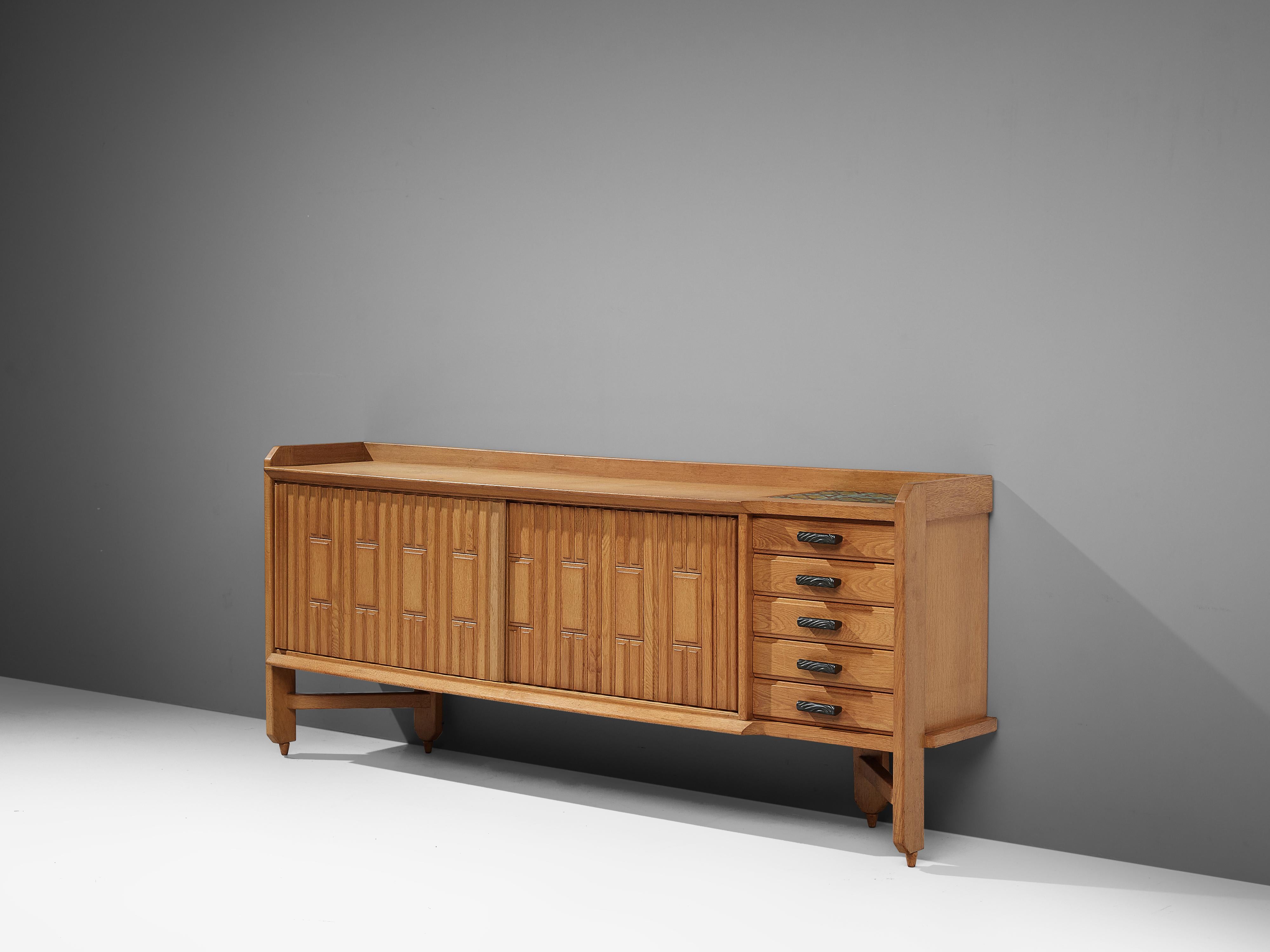Guillerme et Chambron, sideboard, oak, ceramic, France, 1960s

Characteristic sideboard in solid oak with ceramic tiles. This cabinet holds the characteristics of the French designer duo Guillerme et Chambron. The base has typical legs and provides