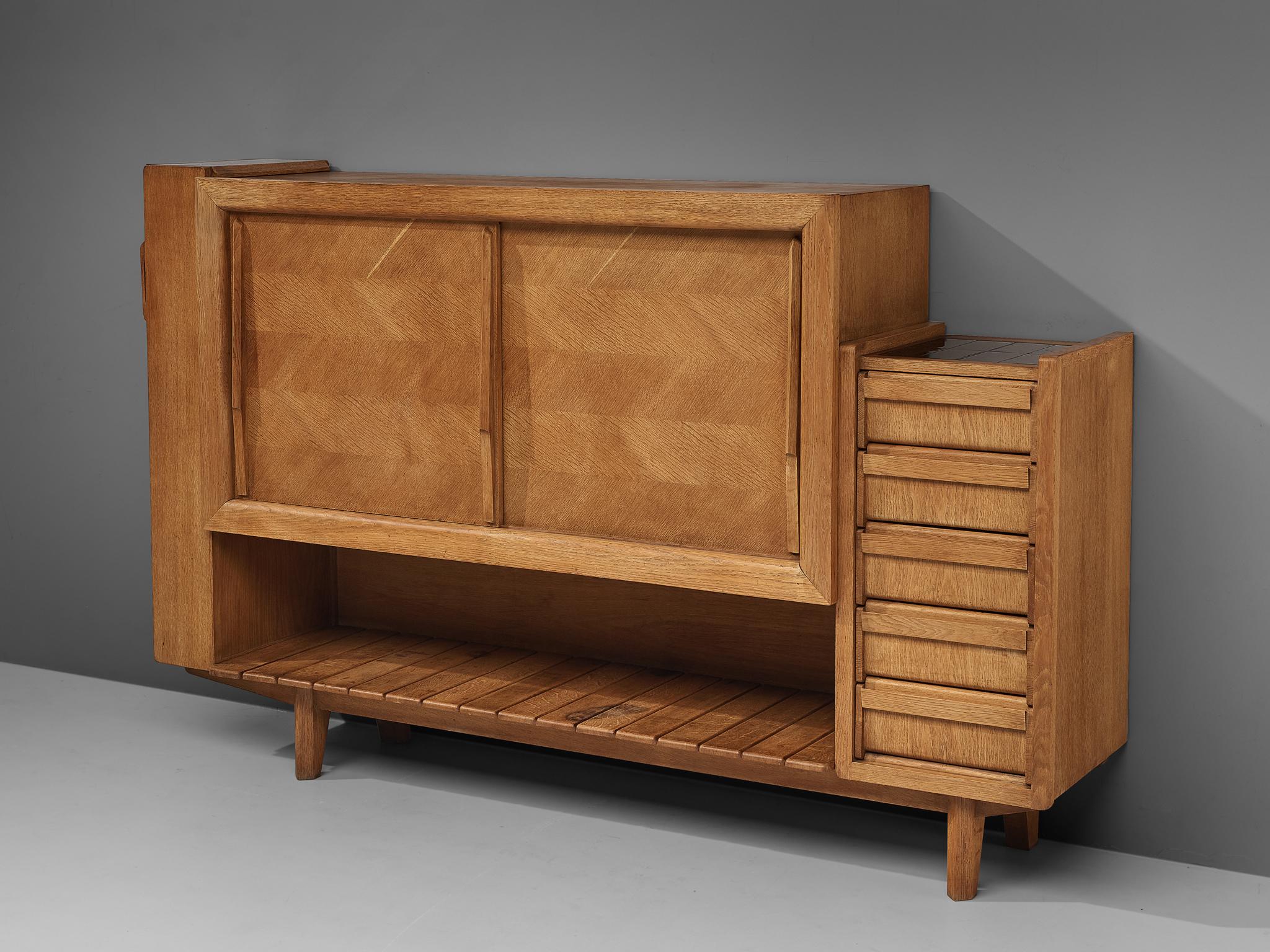 Guillerme et Chambron, sideboard, oak, ceramics, France, 1960s 

Functional credenza by Guillerme et Chambron with black ceramic tiles. This sideboard features four different storage compartments. A compartment with two sliding doors is places above