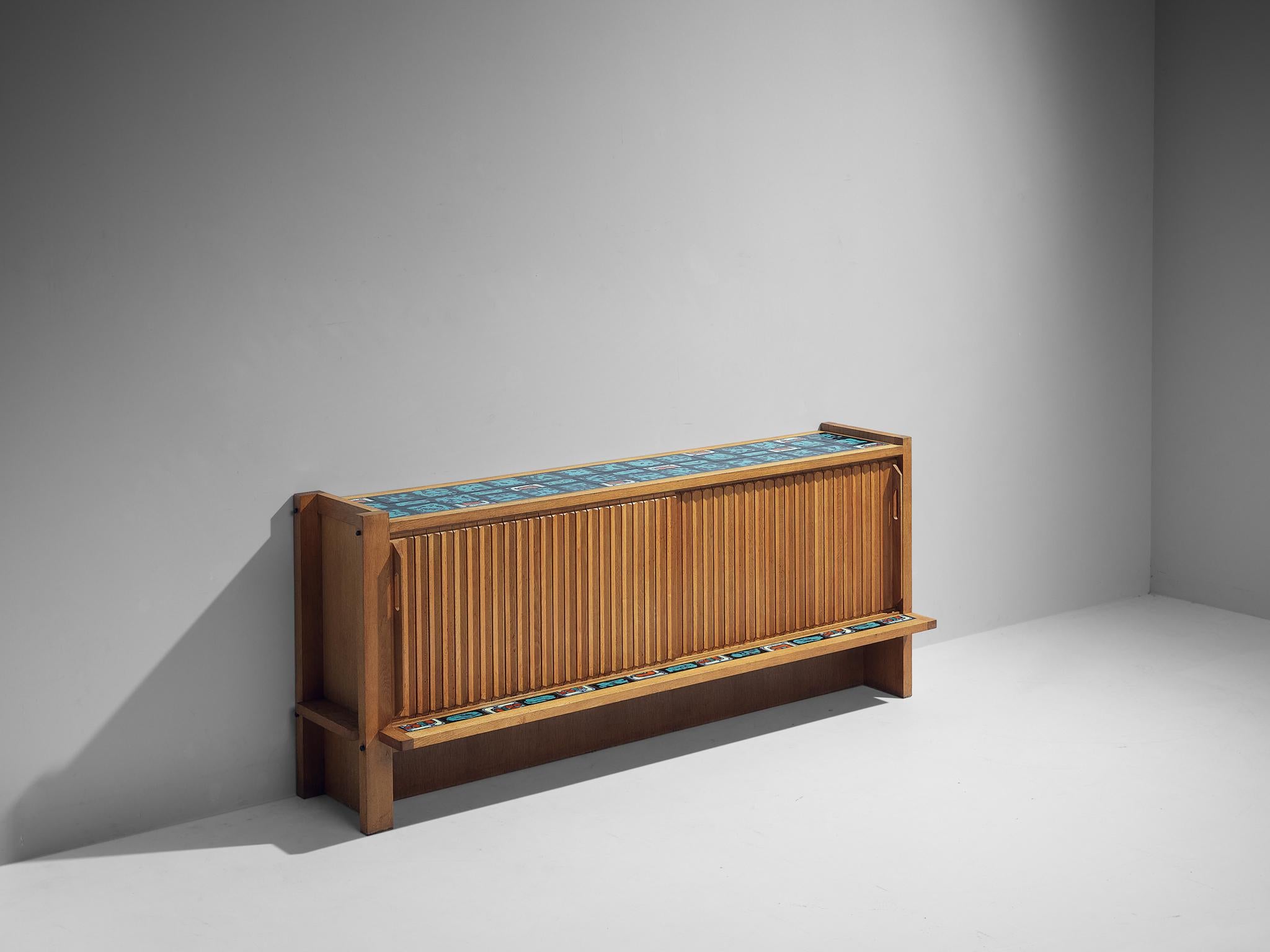Guillerme et Chambron, sideboard, oak and ceramic, France, 1960s.

Outstanding sideboard in solid oak with ceramic tiles glazed in black, red and turquoise on top. This cabinet holds the characteristics of the French designer duo Guillerme et