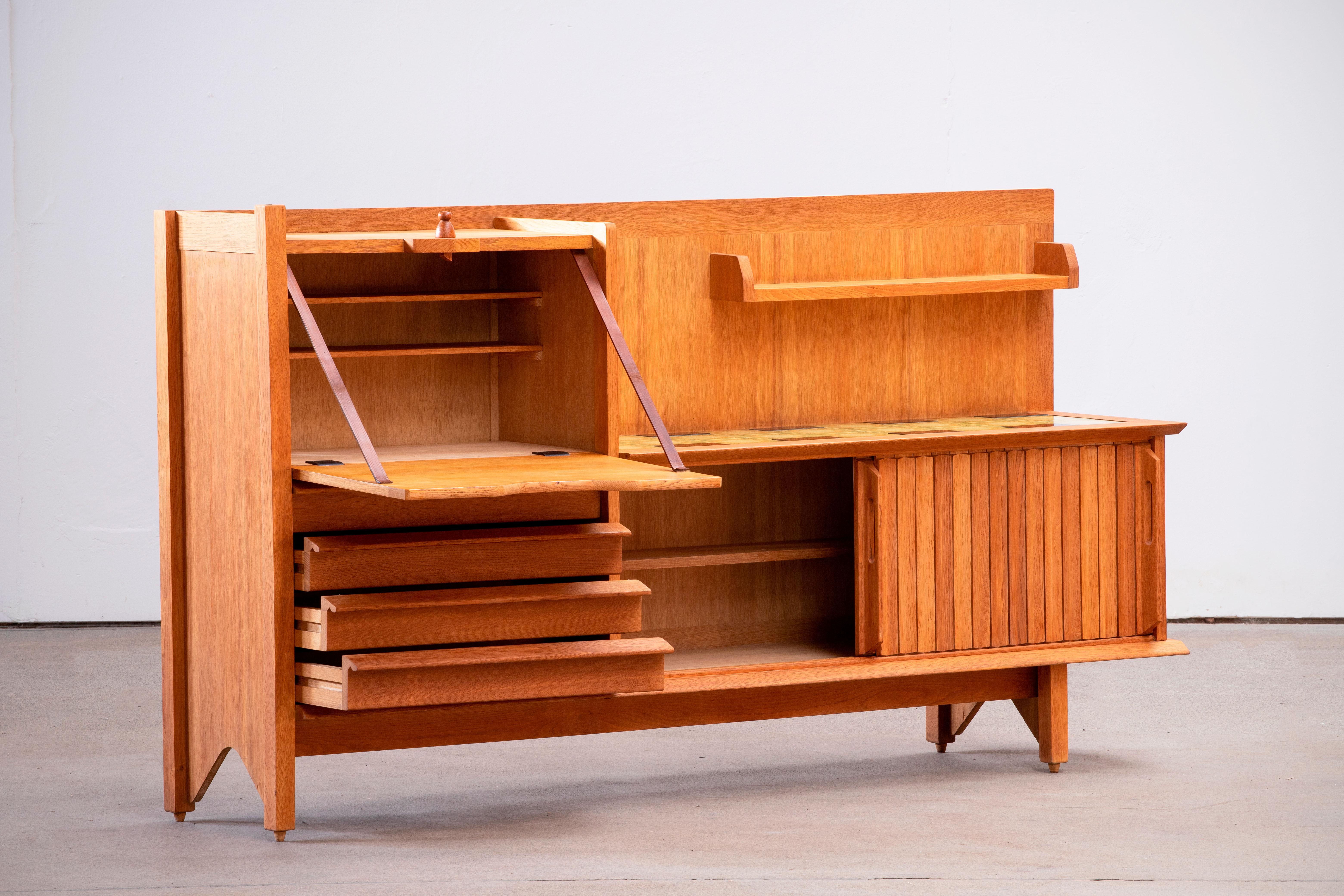 Ce meuble caractéristique, buffet en chêne massif, est conçu par le duo de designers français Jacques Chambron (1914-2001) et Robert Guillerme (1913-1990). Elle comporte deux portes coulissantes, une porte coulissante sur le côté gauche et quatre