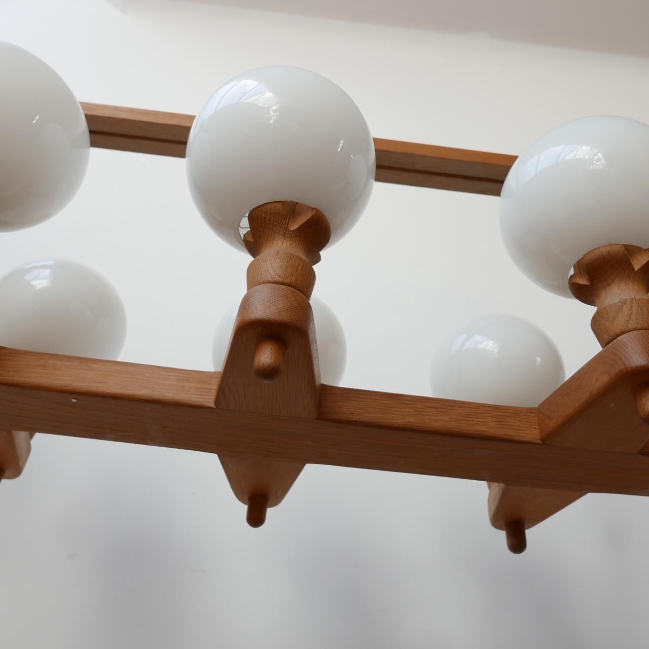 A large oak chandelier by Guillerme et Chambron. 

France, c1960s. 

Opaline glass shades. 

Re-wired and PAT tested. 

Good condition. 

Dimensions: 109 W x 40 D x 45 H in cm. 

Delivery: POA.

  