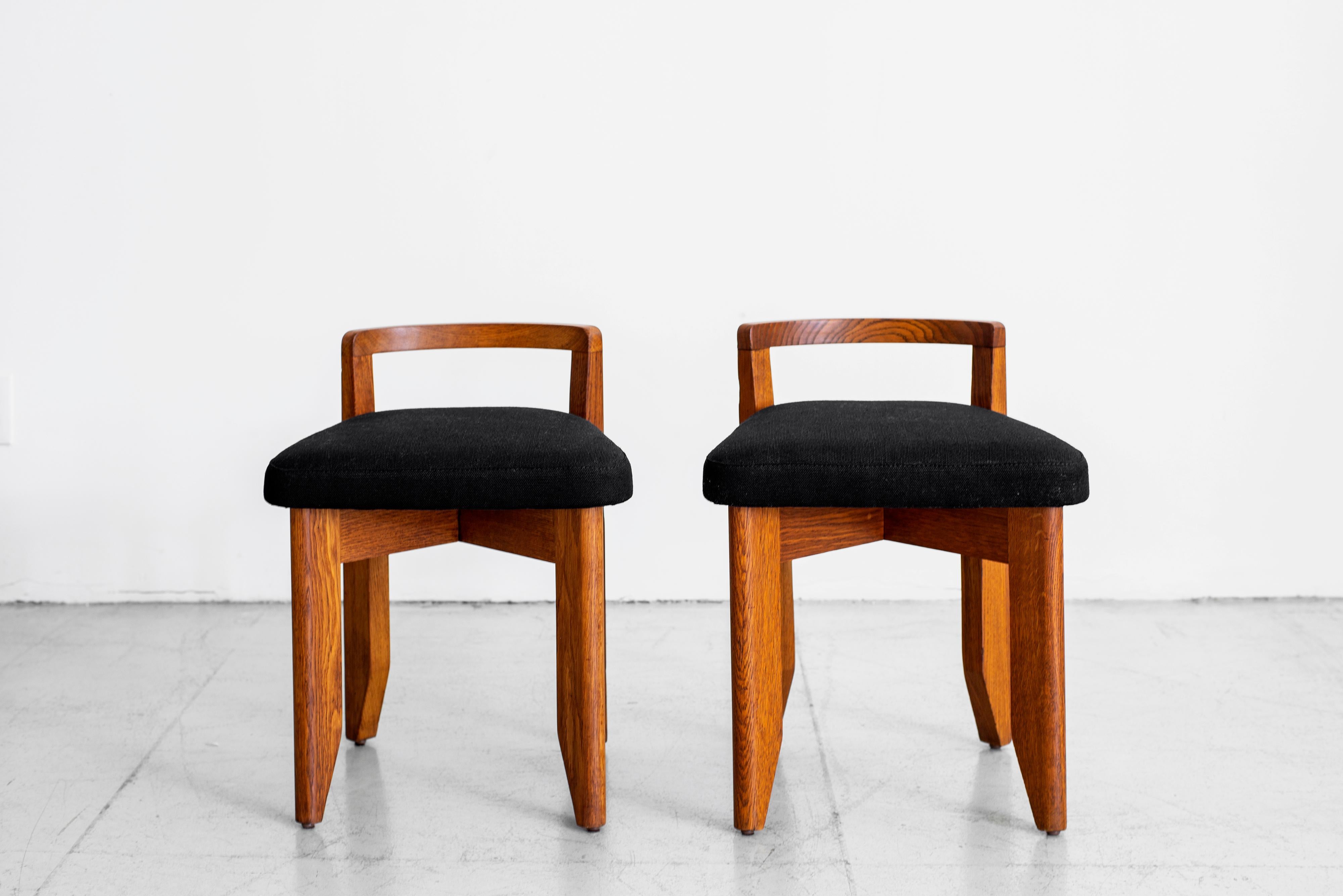 Beautiful pair of oak stools by Guillerme et Chambron with new black linen upholstery. Great patina to wood and petite in scale. Sold and priced individually.