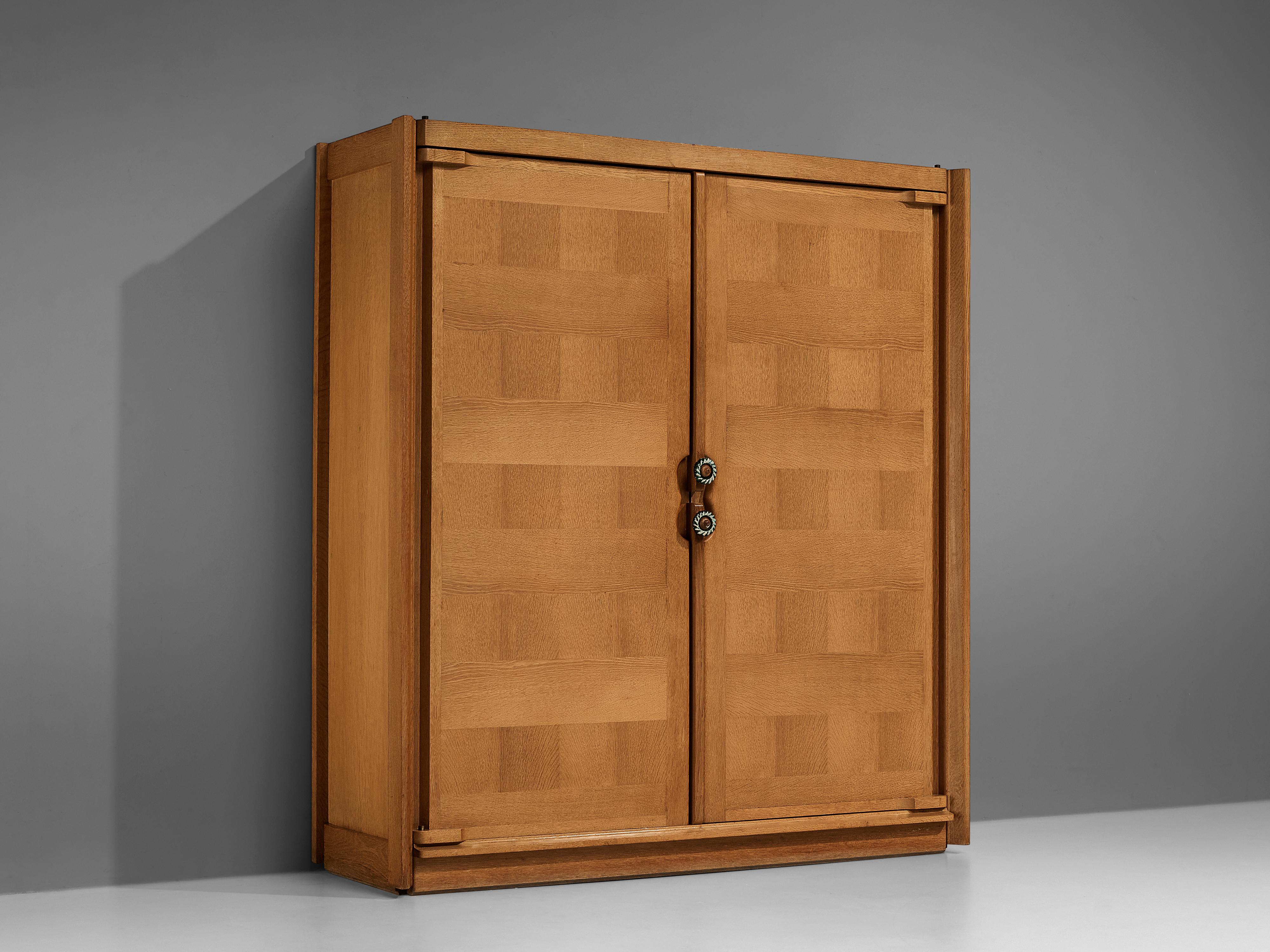 Guillerme et Chambron, armoire, oak, ceramic, France, 1960s.

This case piece is designed by Guillerme and Chambron and features geometric oak inlays, which is characteristic for the French duo. The armoire is equipped with ceramic handles. The