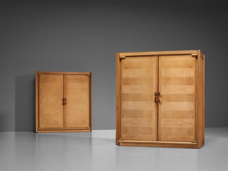 Guillerme et Chambron, armoire, oak, ceramic, France, 1960s. 

This pair of cabinets is designed by Guillerme and Chambron and features geometric oak inlays, which is characteristic for the French duo. The armoire is equipped with ceramic handles.