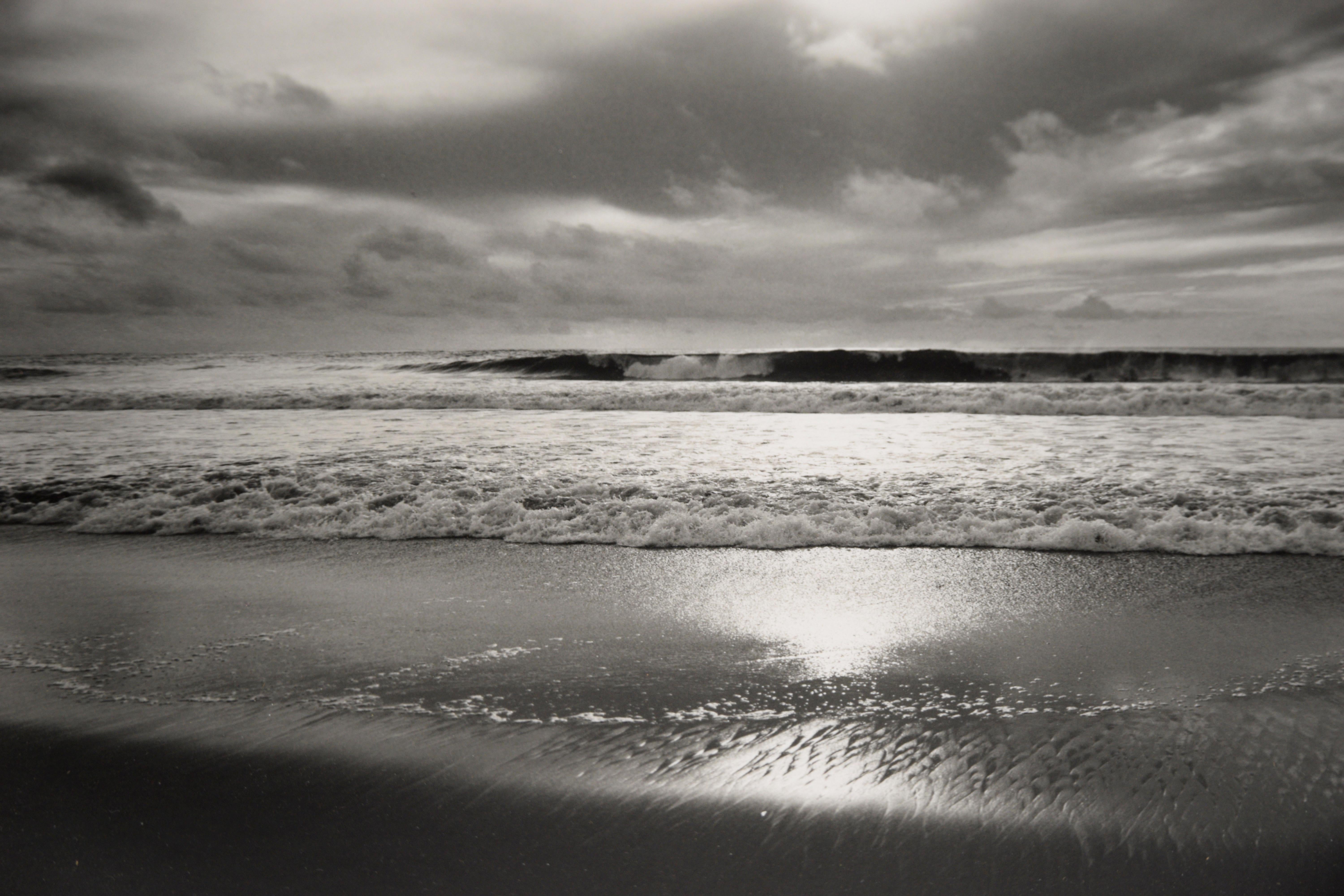 Manhattan Beach, 2003 - Original Black and White Photograph

Original black and white photograph of Manhattan Beach, California by Guillermo Zuniga (American). The viewer looks towards the ocean as waves are crashing ashore. The sun shines through