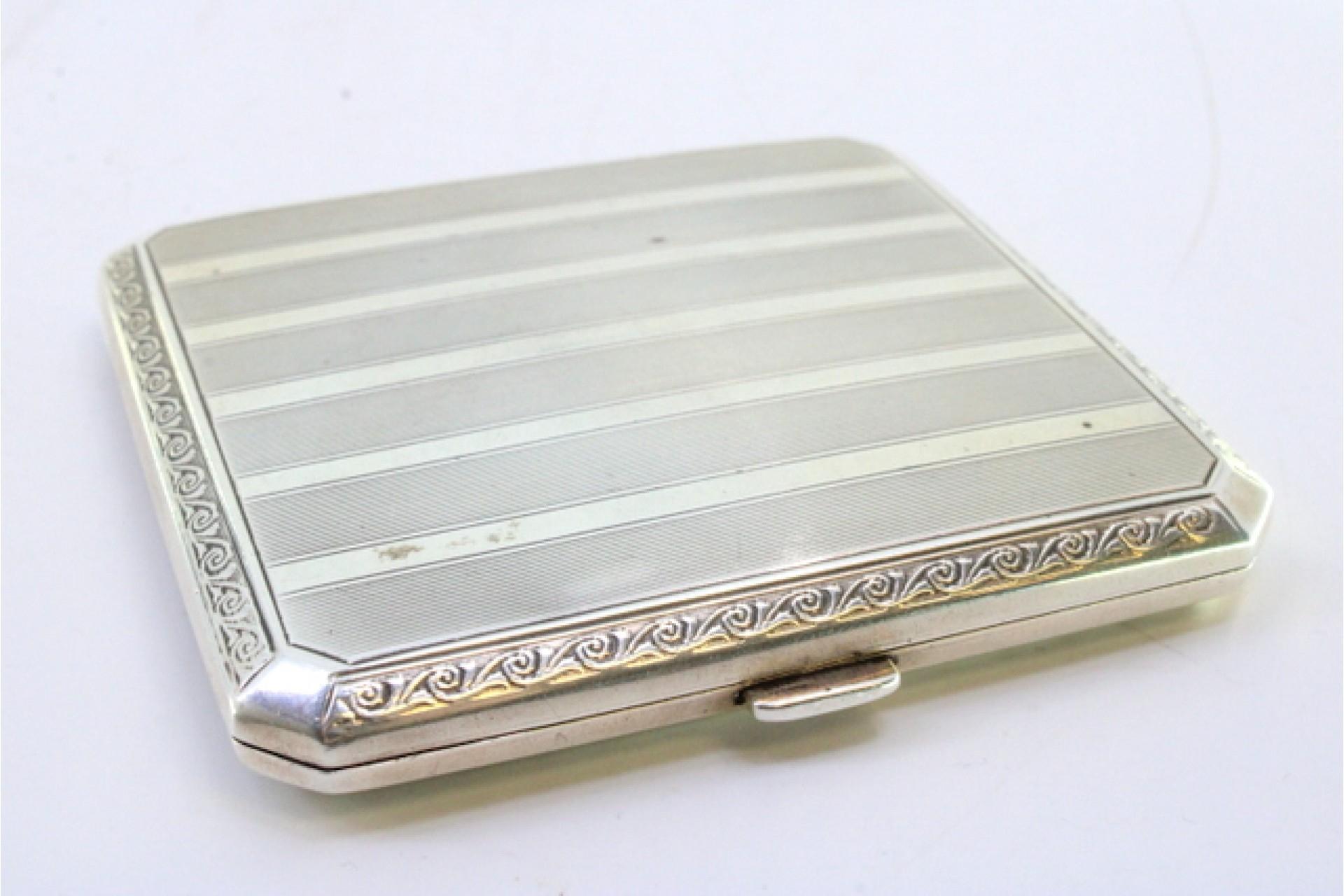 Description: Guilloche silver cigarette case with beveled corners, golden interior bands at the top and hinged lid. Metal: Silver. Origin: European. Brand: Unknown. Weight: 91.72 grams. Dimensions: 8cmx8cm. Content: 935/1000. Assay Mark: Yes.