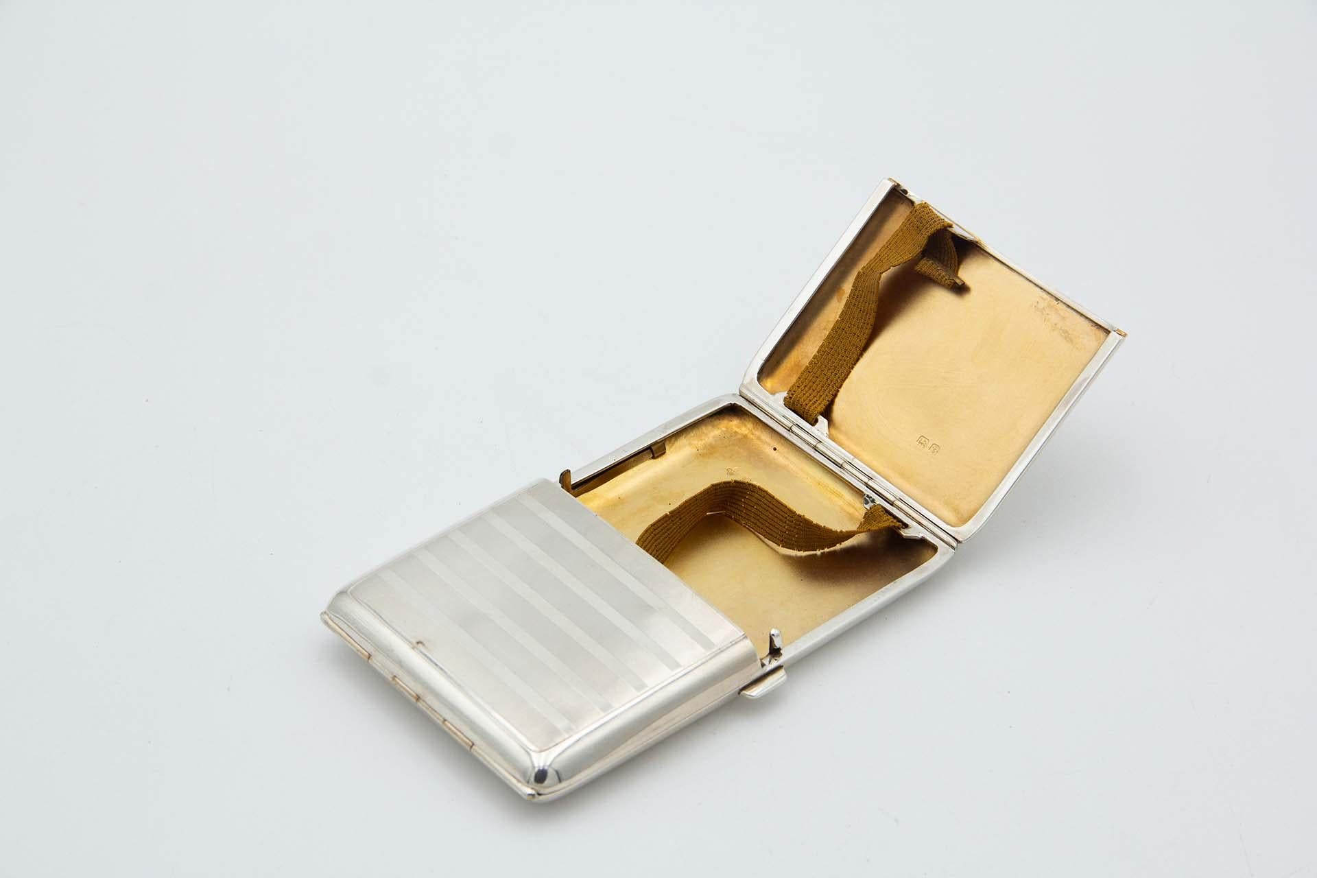 Description: Guilloche silver cigarette case with alternating bands at the top, rectangular in shape with two hinged spring lids and gold interior. Metal: Silver. Origin: English. Brand: Birmingham. Weight: 257.41 grams. Dimensions: 13cmx1.8cm.