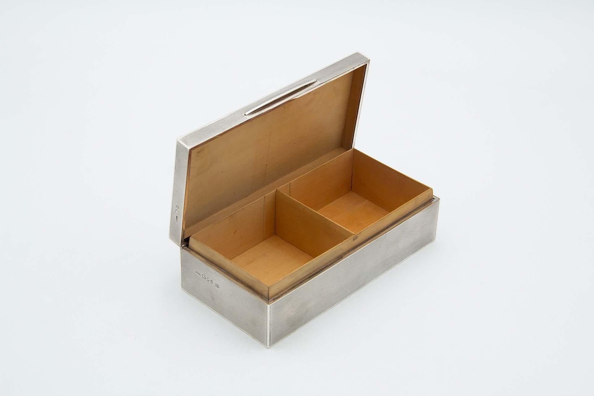 Description: Guilloche silver tobacco box with wood-lined interior. Metal: Silver. Origin: English. Brand: London. Weight: 710.30 grams. Dimensions: 17.9cmx5.2cm. Content: 925/1000. Assay mark: Yes, 1974 by Asprey&Co Limited. Additional information: