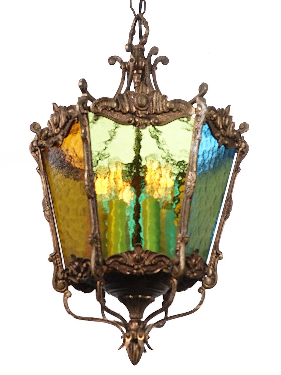 For its size this is a very rich chandelier. Its illuminated by cluster of 6 candle style E12 bulbs. The heavy bronze floral pattern frame holds 6 panels of hammered pattern glass in amber blue and green. Its the perfect main entrance hall