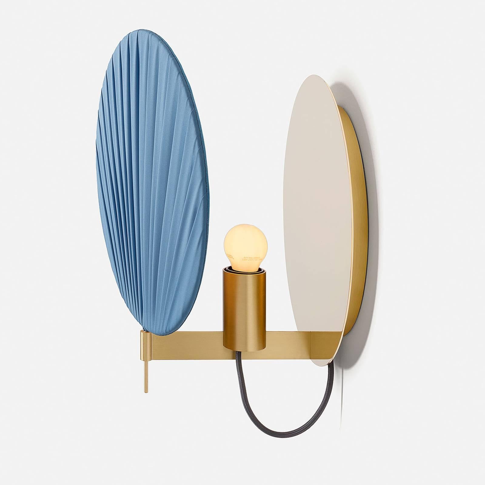 A sophisticated piece of functional decor that will enrich a modern home, this wall lamp features a structure made up of a solid brass disk attached to the wall and a bracket in natural-finished brass. The shade is made of a disk of plated organza,