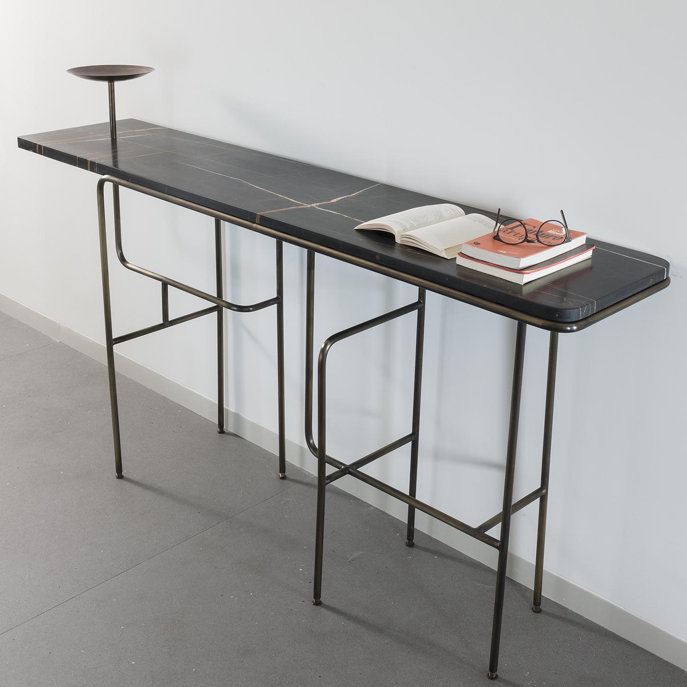 Characterized by an intricate Industrial style, the Guinea console table by Alberto Guarriello is a stylish and functional table that combines a sturdy and solid marble top with an interwoven support structure of burnished brass tubing providing a