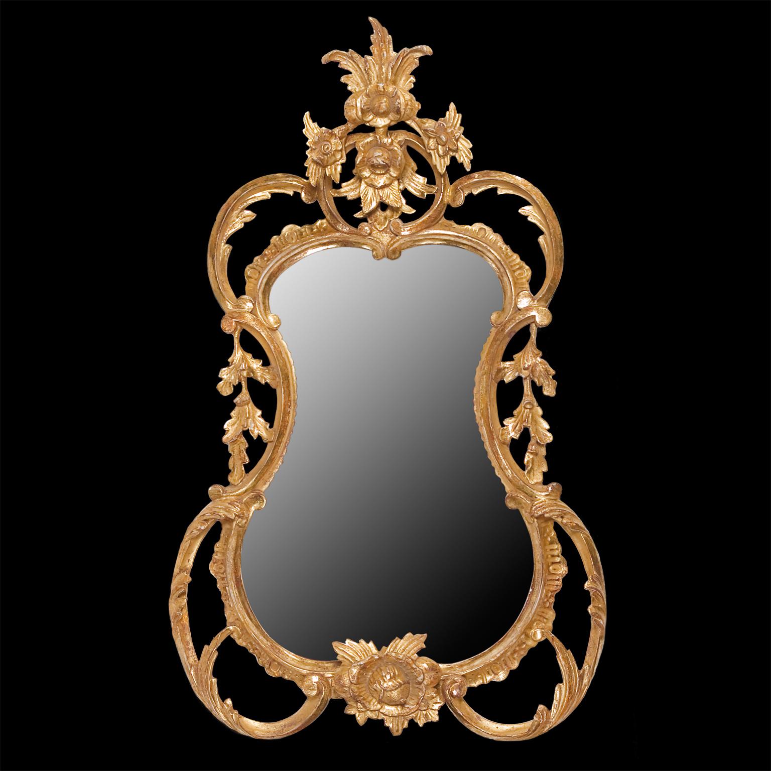 A small carved giltwood looking glass mirror in a swirling Rococo style frame incorporating many of the mid-18th century designers repertoire of vigorous leaf carved scrolls, leaves and flowers.

We are currently working to a 30-36 week lead time.
