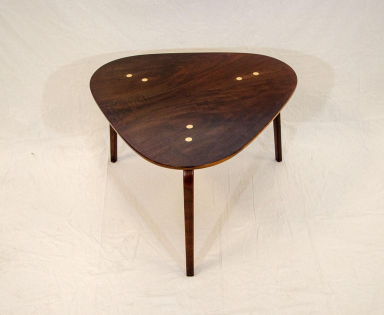 A nice mid-century walnut guitar pick low table that can be used between two lounge chairs as well as a coffee table for a small space. The top is accented by three sets of two brass inset discs. The bottom is marked 