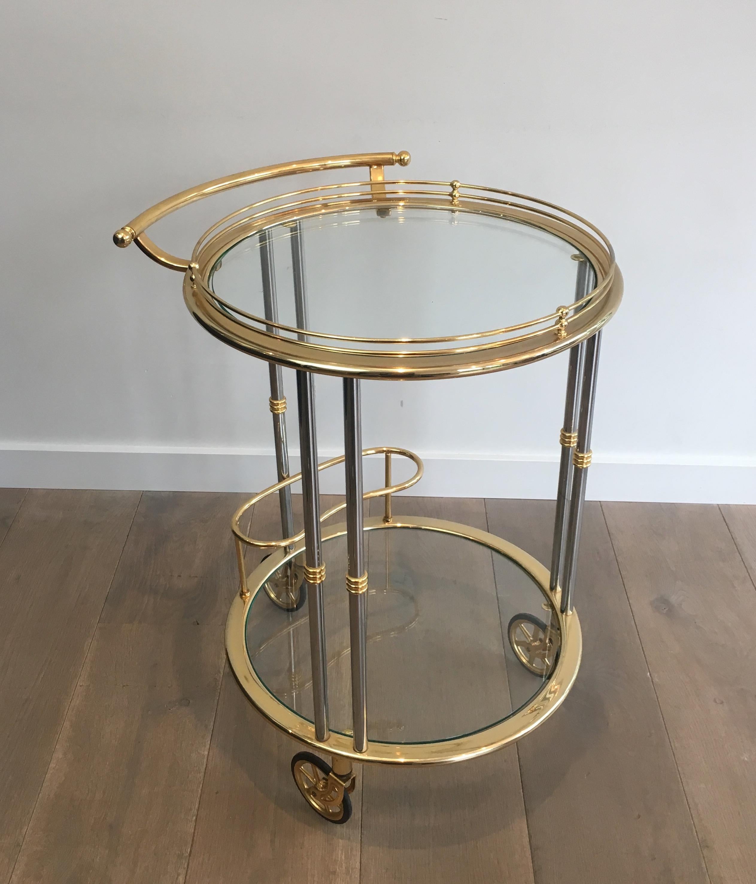 This round bar cart is made of gun metal and gilt metal with 2 clear glass shelves. This drinks trolley is a French work, circa 1970.