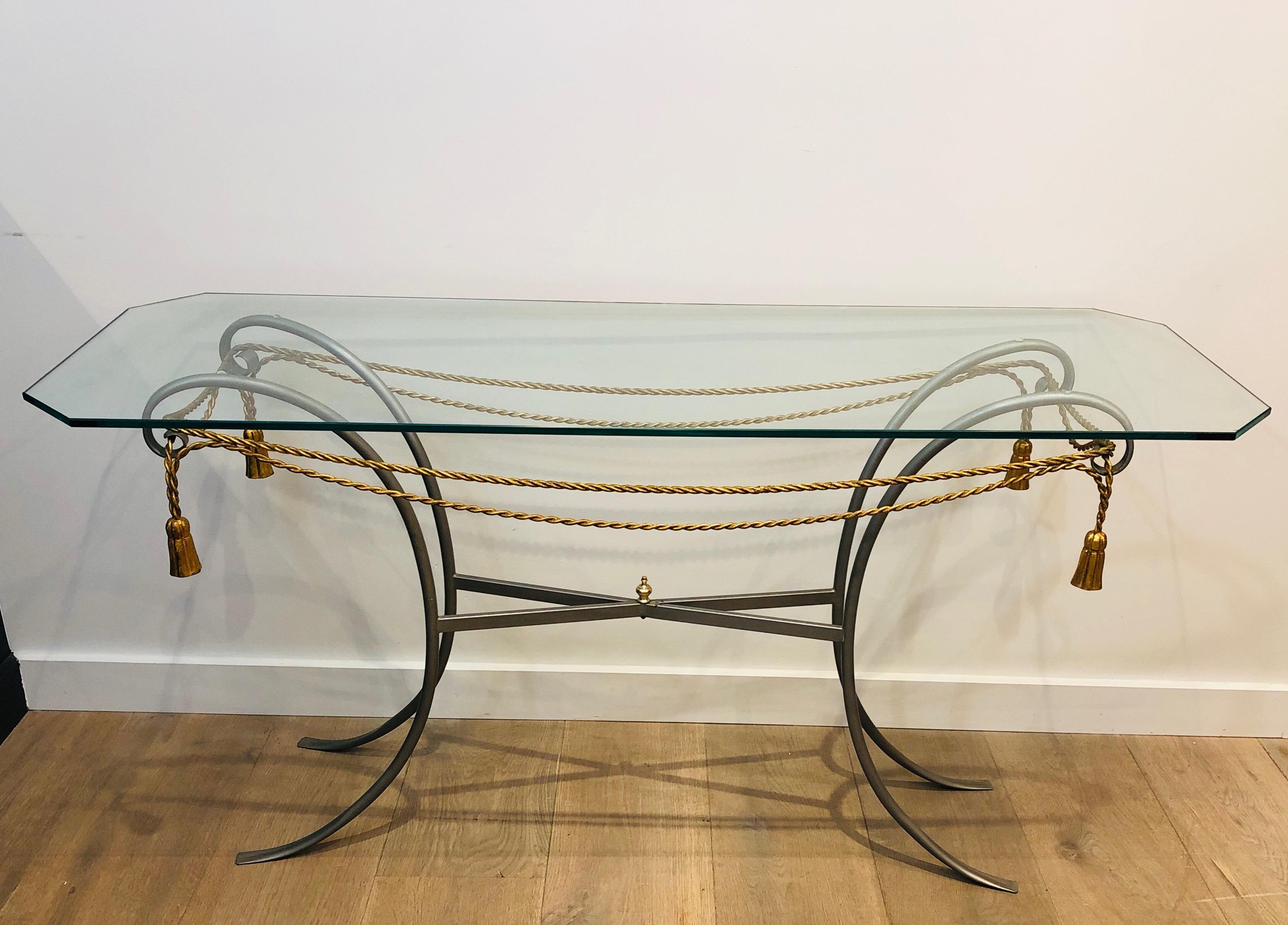 This nice and decorative console table is made of gun metal, gilt metal garlands and pompons with a glass top. This is the Coco Channel Model, a French work, circa 1970.