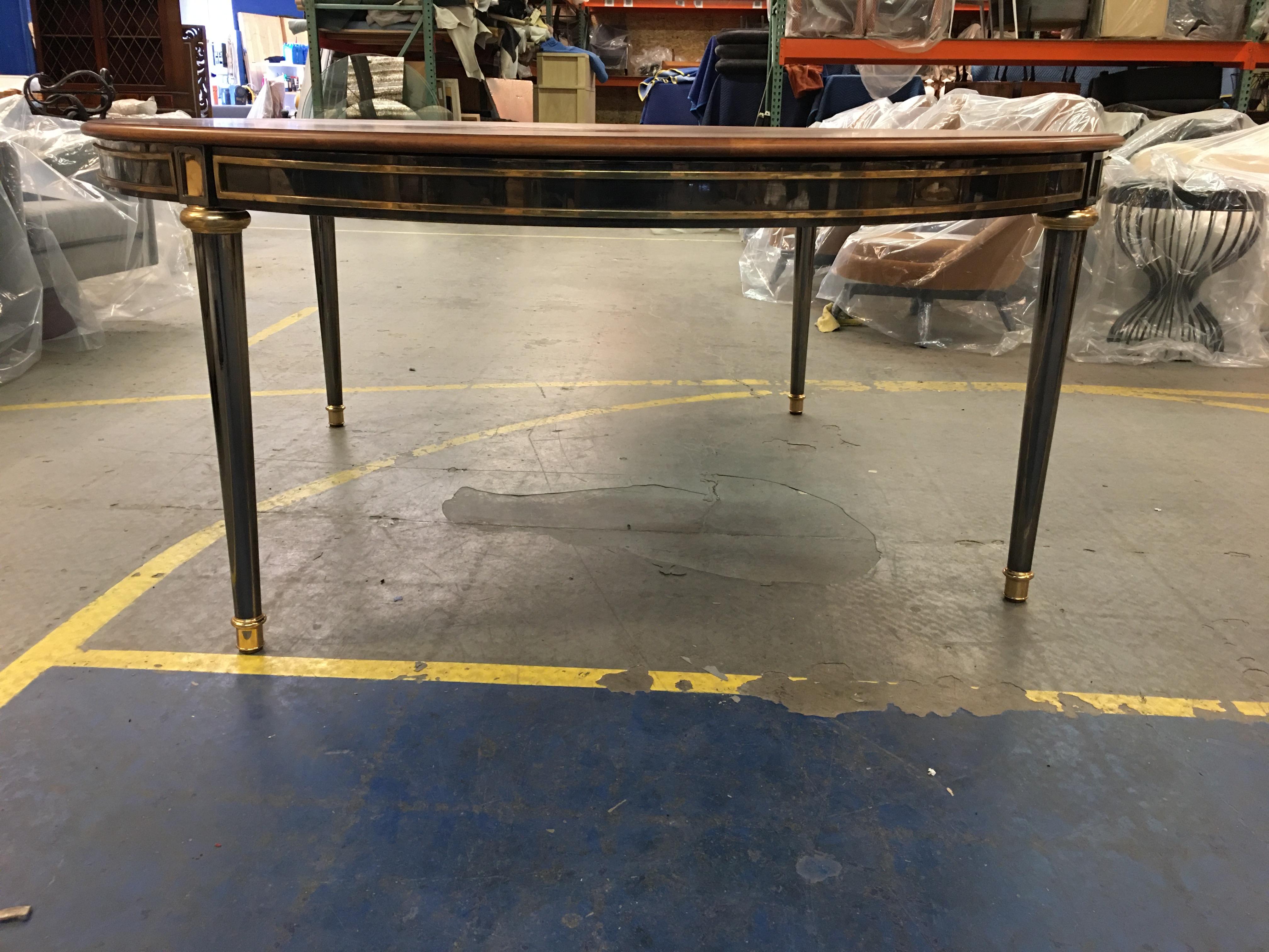 Fabulous and large scale gunmetal and brass dining table in the style of Jansen. The entire Directoire style table is constructed of polished brass, with the base of gunmetal plated brass. The legs are solid brass (not hollow cast) brass plated in