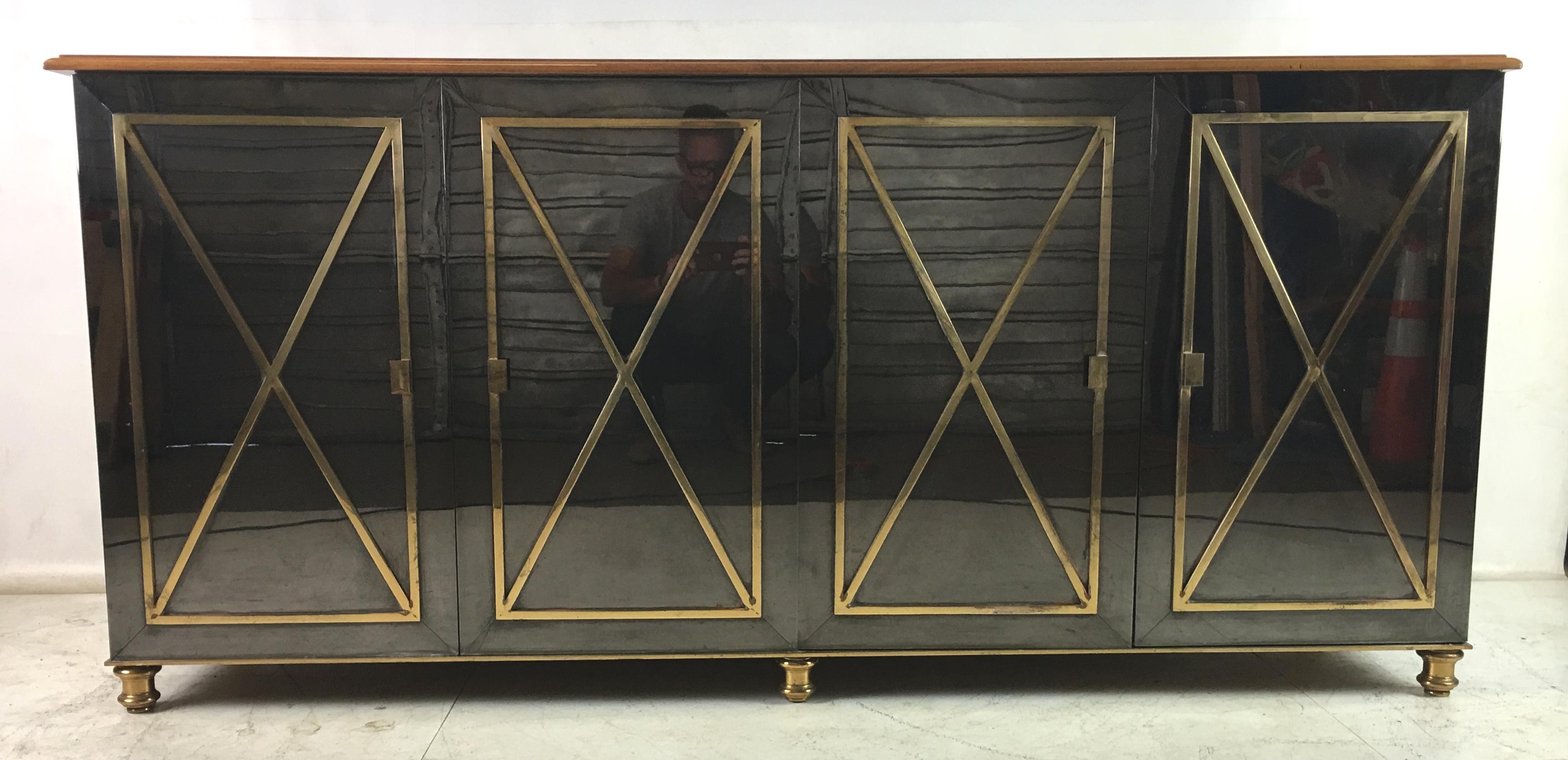 Spectacular neoclassical modern gunmetal sideboard with brass fittings and walnut top. The cabinet is entirely clad in gunmetal plated steel with solid brass ornamentation and turned brass bun feet. The interior, its four shallow drawers and