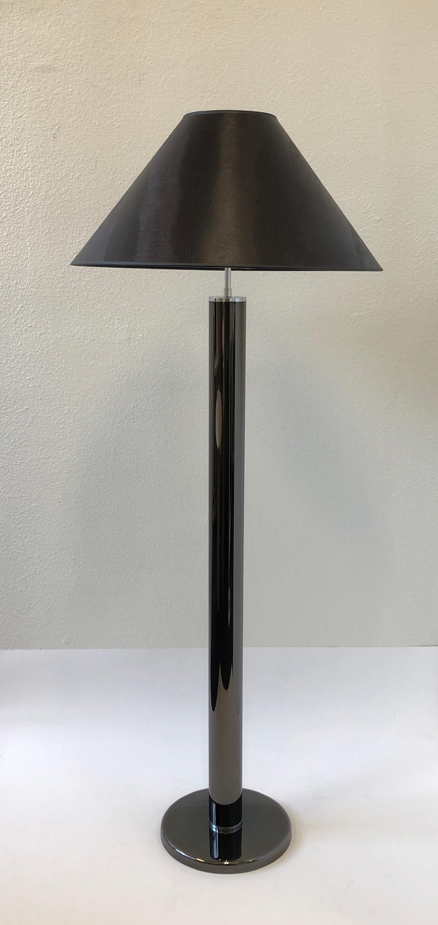 A glamorous 1970s gunmetal and chrome floor lamp by American renowned designer Karl Springer. The lamp has been newly rewired and has a new chocolate brown faux lizard shade.
Overall dimensions: 51.5” high 24” diameter 12” diameter base.