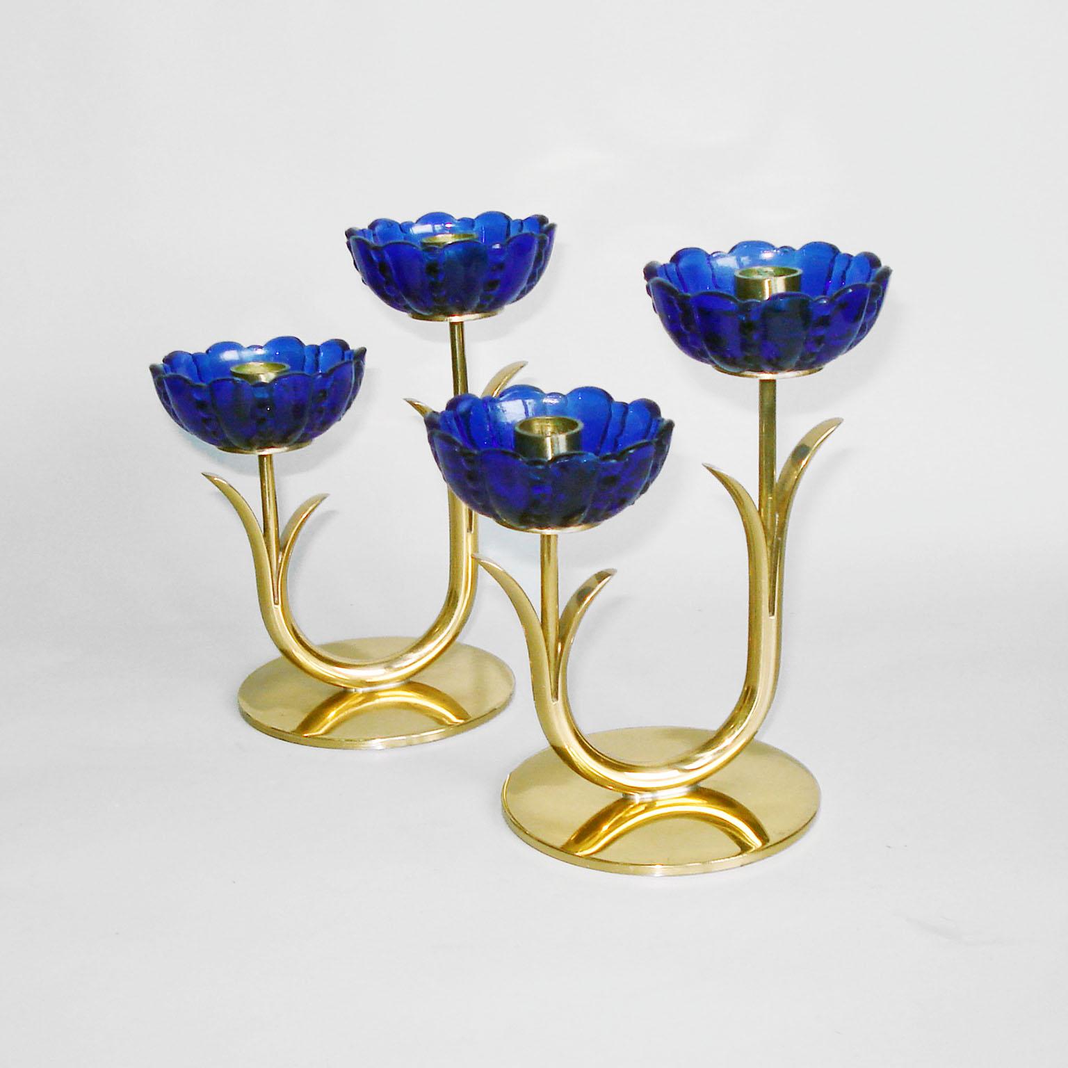 A pair of candle holders designed by Gunnar Ander for Ystad Metall, Sweden, 1950s. 
A double light candleholder flower shaped, with blue transparent art glass, mounted on a brass/bronze stem, fixed on a round base. Marked on the bottom. 
Very good