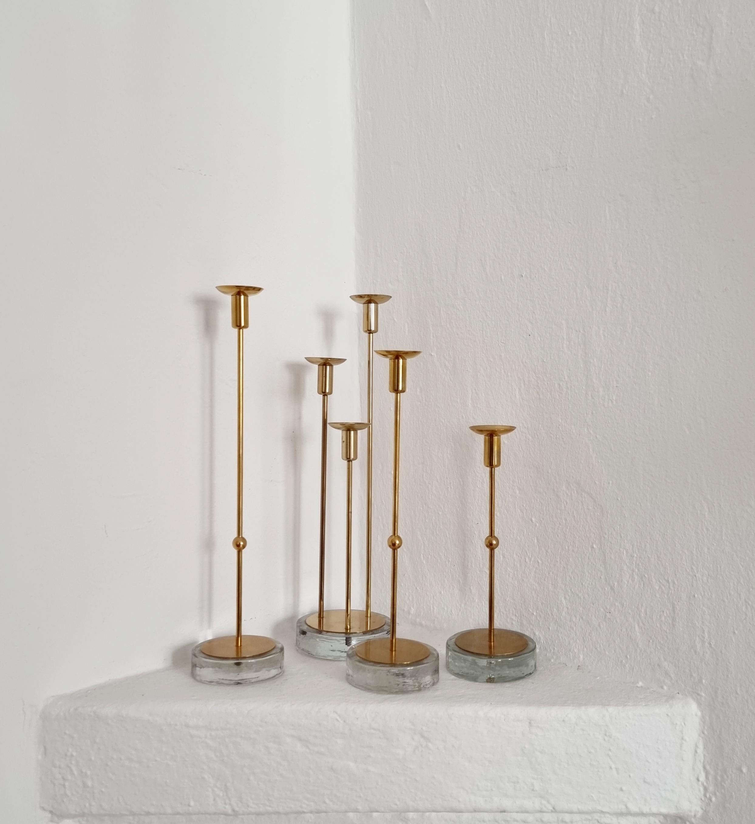A rare set of four candle holders, one for three candles (total for six candles). Delicate shape, still stabile, a decorative set for thin candles. Designed by Gunnar Ander for Ystad Metall, Sweden 1960s. In solid brass with glass base. 

A box