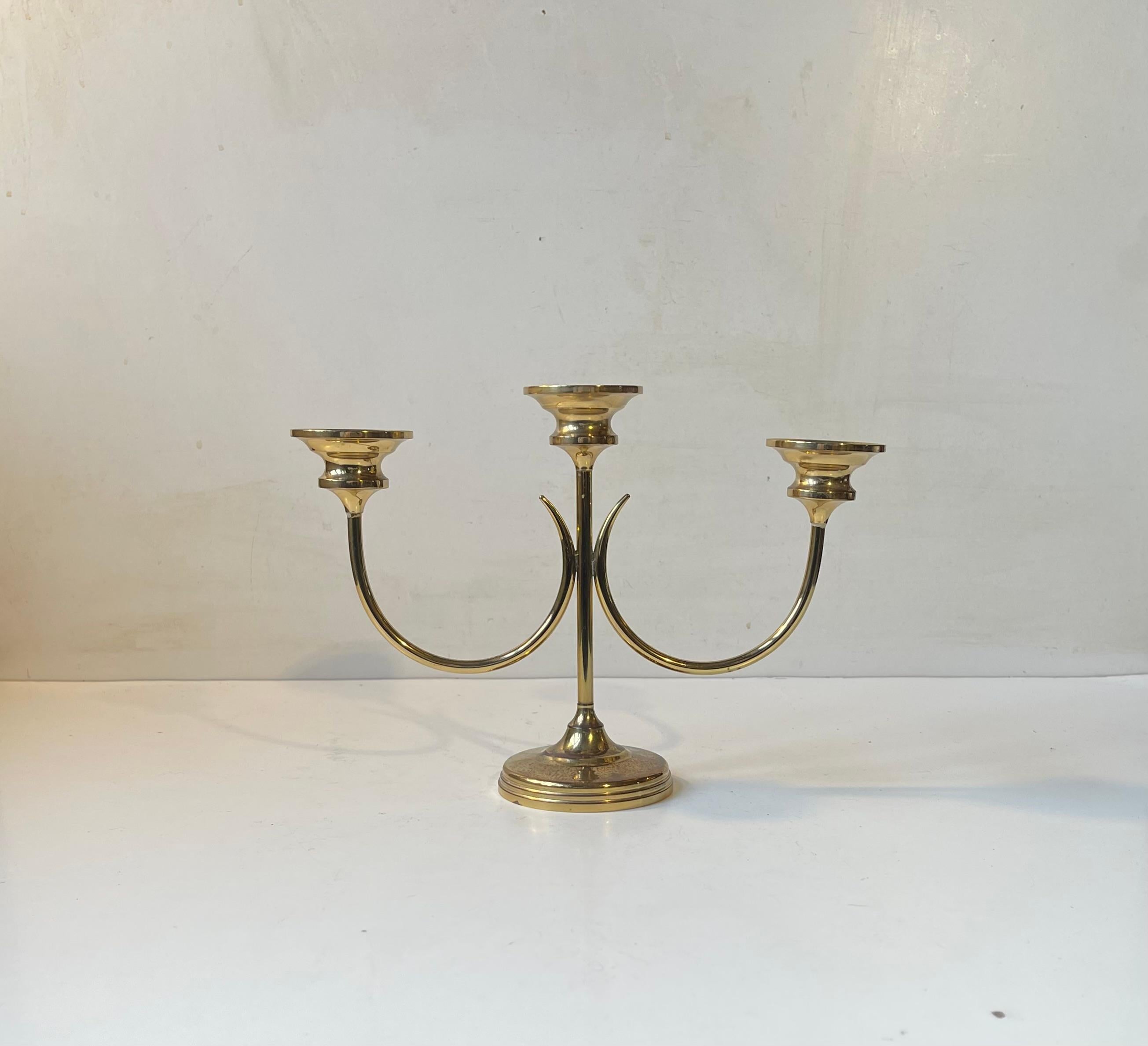 Stylized lily candelabra in solid brass. Its to be fitted with 3 regular sized candles. Designed by Swedish Gunnar Ander circa 1960-70. Reminiscent in style to Ivar Ålenius Björk iconic candlesticks. Measurements: H: 18 cm, W: 24,4 cm, Diameter