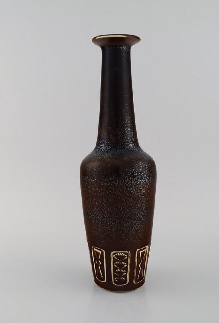 Gunnar Nylund (1904-1997) for Rörstrand. 
Bottle-shaped vase in glazed ceramics. Beautiful speckled glaze in brown and metallic shades. Leaves and geometric patterns in relief. 
Mid-20th century.
Measures: 33.5 x 10.5 cm.
In excellent