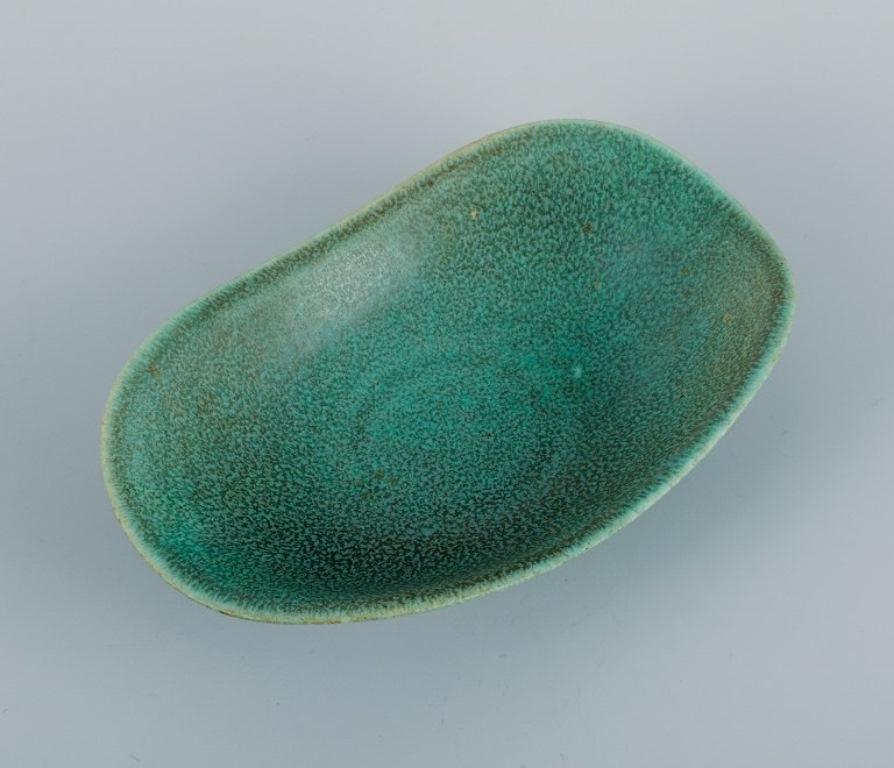 Gunnar Nylund (1904–1997) for Rörstrand. 
Ceramic bowl in organic shape with mottled green glaze.
Mid-20th century.
In perfect condition.
Marked.
Dimensions: L 17.0 x H 4.0 cm.