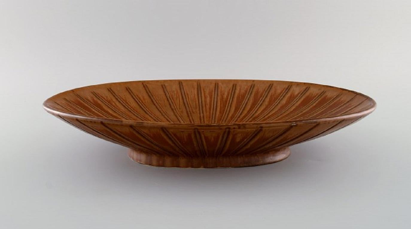 Gunnar Nylund (1904-1997) for Rörstrand. 
Large and rare bowl in glazed ceramics. Beautiful glaze in brown shades. 
Mid-20th century.
Measures: 40 x 26 cm.
Height: 7 cm.
In excellent condition.
Signed.
1st factory quality.