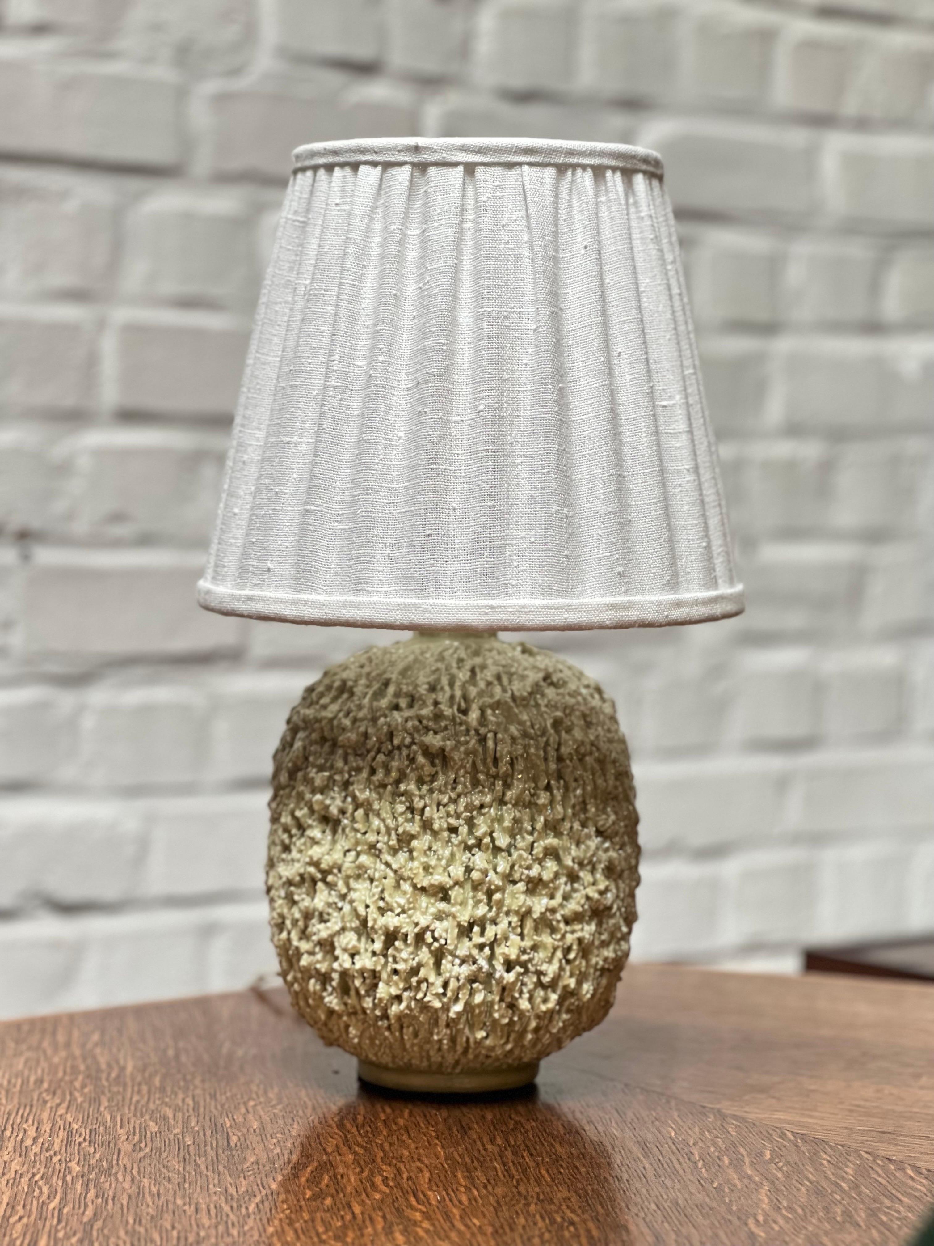 This is a real lamp in mother of pearl finish by Swedish master ceramicist Gunnar Nylund. Made in 1936. It's a real lamp not as most of them a vase transformed as a lamp. There's a new high quality white linen shade, made on measurements to fit the