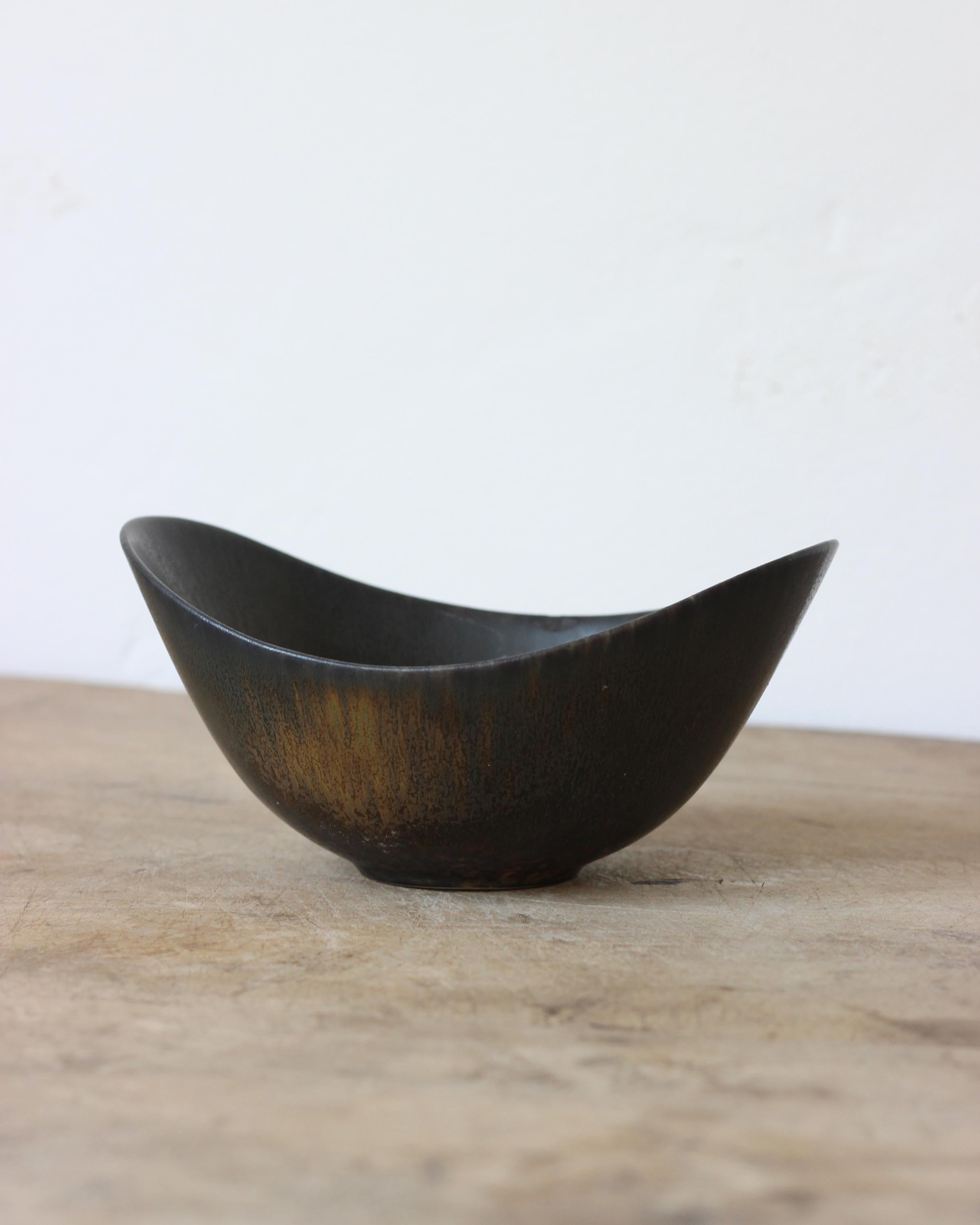 Beautiful and rare bowl by Gunnar Nylund in a dark glaze with hues of black, navy, brown. Rörstrand produced in the 1950s. In good vintage condition showing small signs from age and use. Signed on bottom.