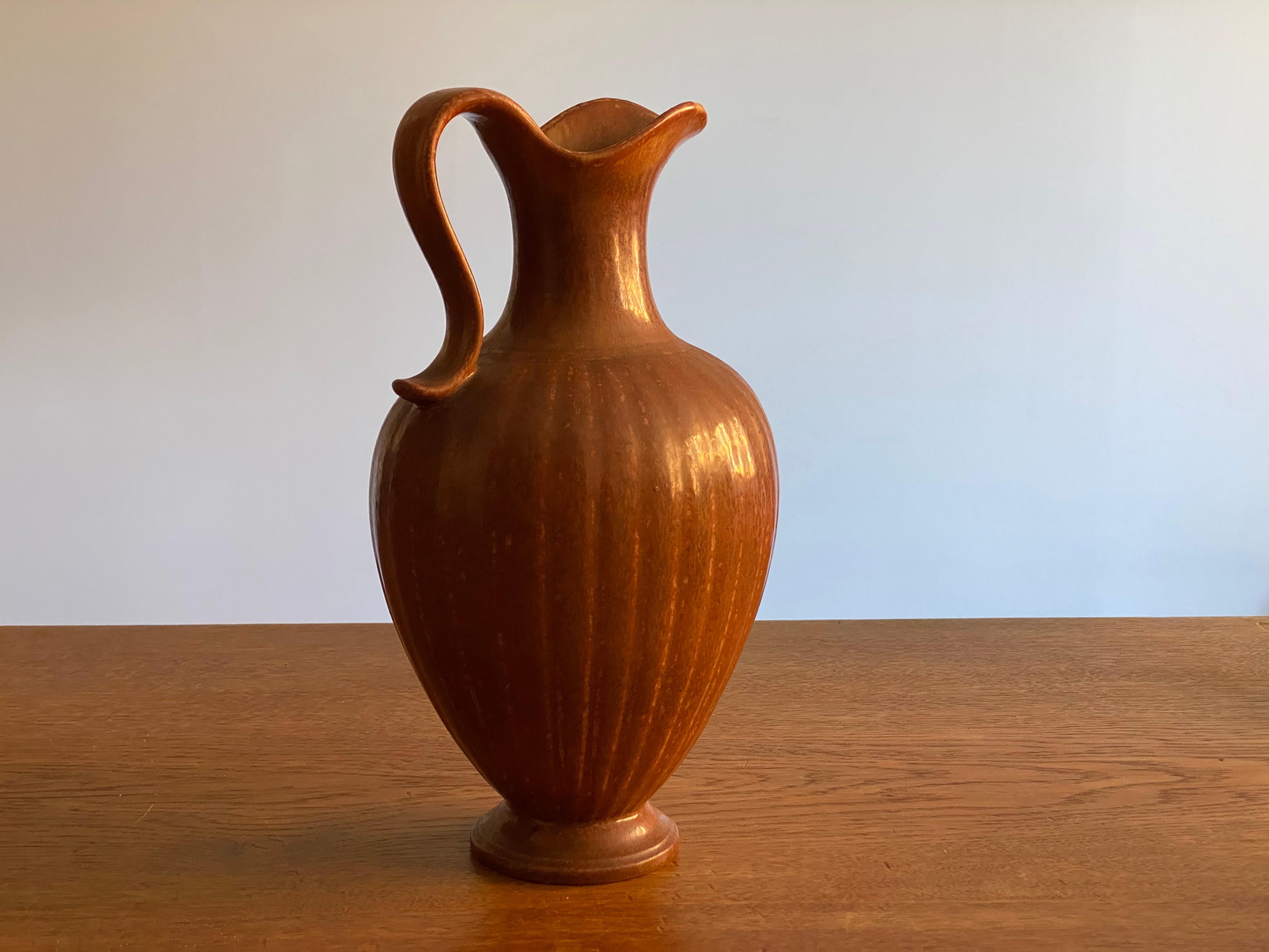 A sizable stoneware pitcher produced by Rörstrands, Sweden, 1940s. Designed and signed by Gunnar Nylund, (Swedish, 1914-1997).

Nylund served as artistic director at Rörstrands, where he worked 1931-1955. Prior to his work at Rörstrand he was a