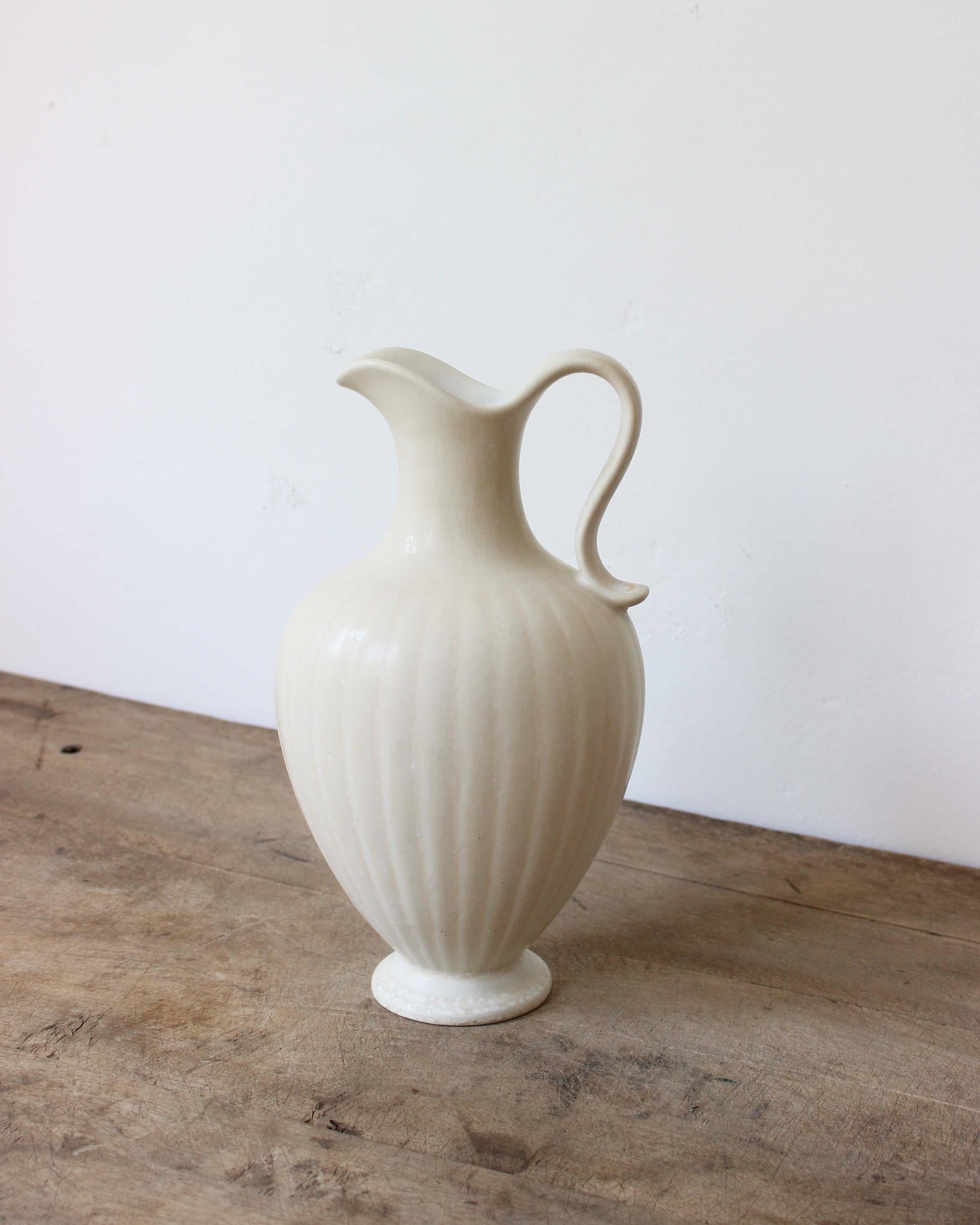 Impeccable stoneware pitcher produced by Rörstrands, Sweden, 1940s. Designed and signed by Gunnar Nylund, (Swedish, 1914-1997).

Nylund served as artistic director at Rörstrands, where he worked 1931-1955. Prior to his work at Rörstrand he was a