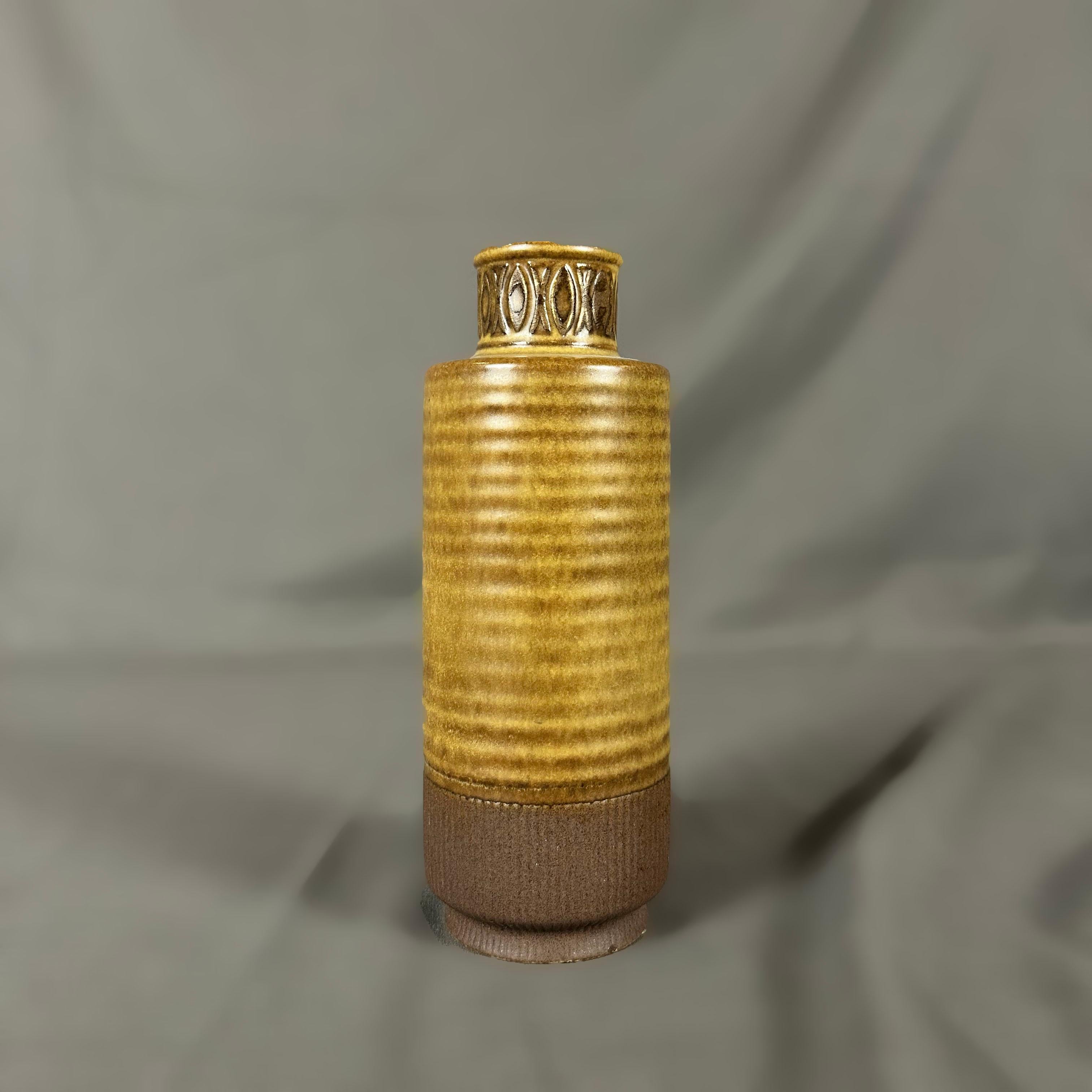 Conçu par Gunnar Nylund en 1964 pour la Collection S, ce vase cylindrique émaillé brun moutarde avec des reliefs géométriques est une belle pièce de céramique suédoise. Signé avec Rörstrand 