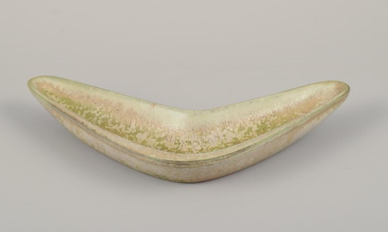 Gunnar Nylund for Rörstrand. Boomerang-shaped ceramic bowl.
Eggshell glaze in light green and sand-colored tones.
Mid-20th century.
Marked.
In perfect condition.
Second factory quality.
Dimensions: W 21.0 cm x H 2.5 cm.