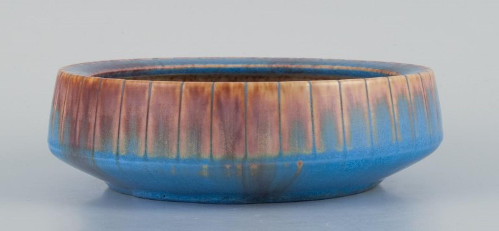 Gunnar Nylund for Rörstrand. 
Ceramic bowl with glaze in blue and brown tones.
Mid-20th century.
Marked.
In excellent condition.
Second factory quality.
Dimensions: Diameter 17 cm, Height 5.0 cm.