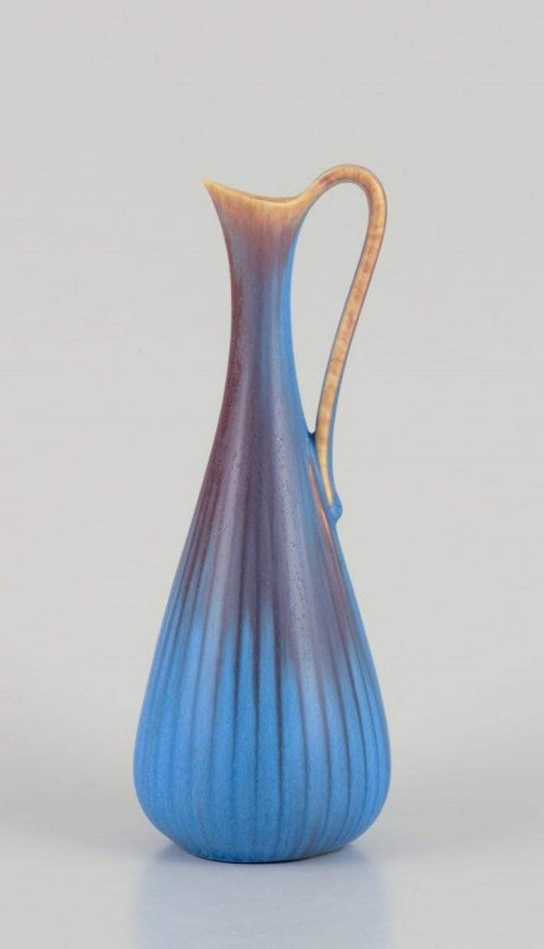 Gunnar Nylund (1904-1997) for Rörstrand. Ceramic pitcher with a glaze in blue and brown tones. Slender form.
Mid-20th century.
Marked.
In good condition with minimal chipping at the spout.
Second factory quality.
Dimensions: Height 19.0 cm x