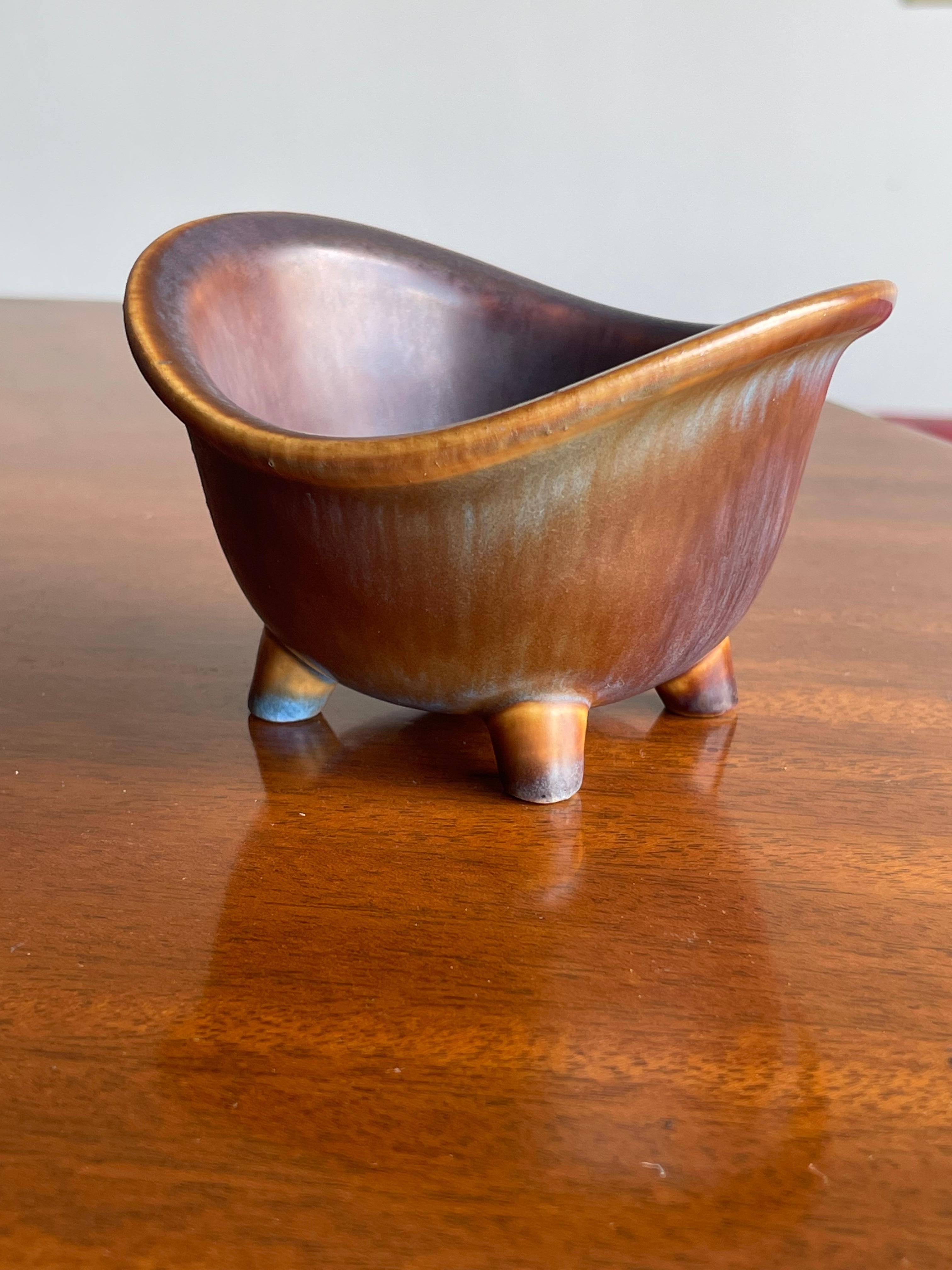 Rare footed bowl designed by Gunnar Nylund for Rörstrand. Wonderful glaze with a amber body and tones of brown to blue. Unique design with footed base. Signed on underside with the 