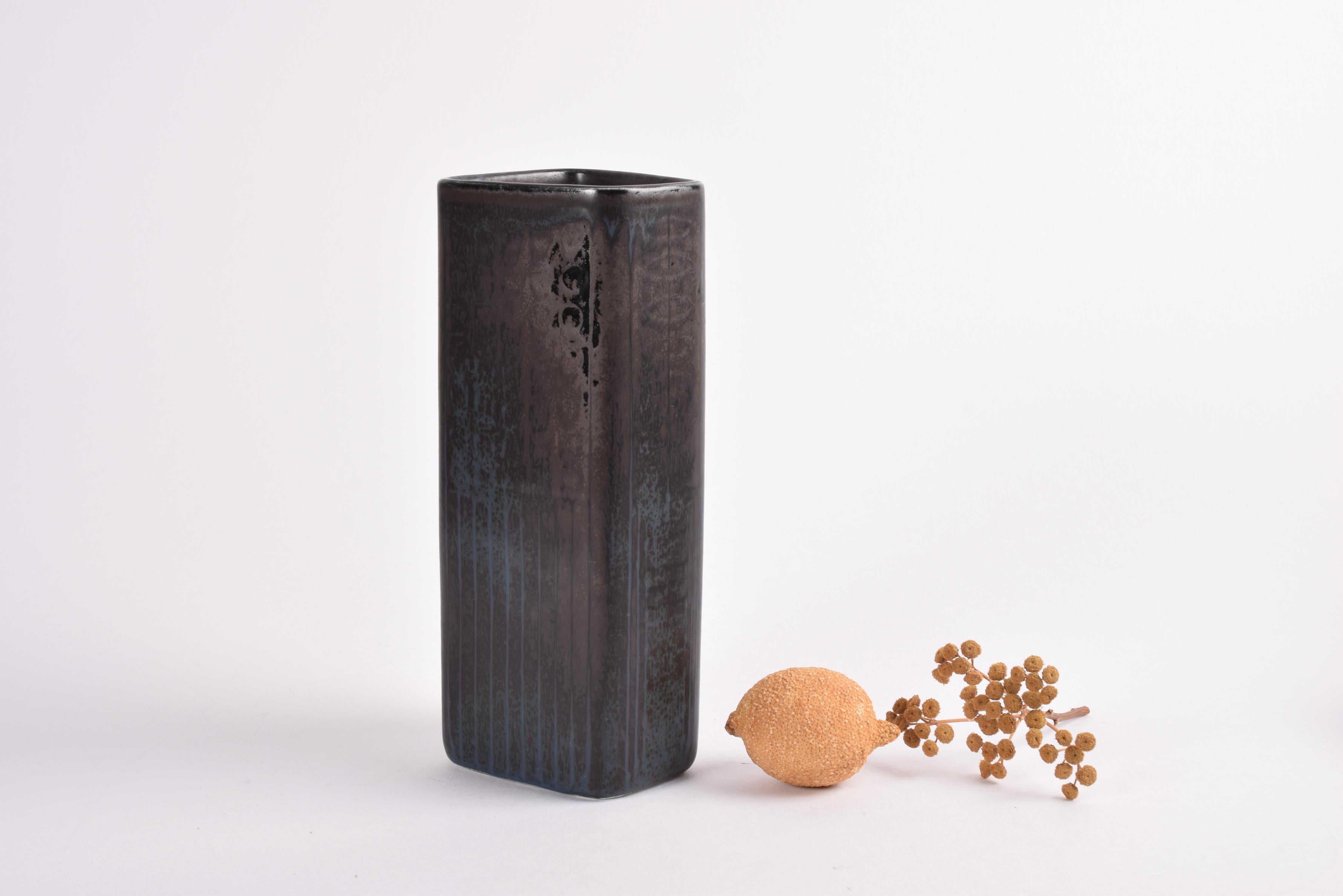 Midcentury ceramic vase by Gunnar Nylund for Rörstrand Sweden.
Made circa 1950s to 1960s.

The vase features an interesting glaze with a semi matte black, dark brown and blue-gray glaze with a few glossy black elements over incised decor. The