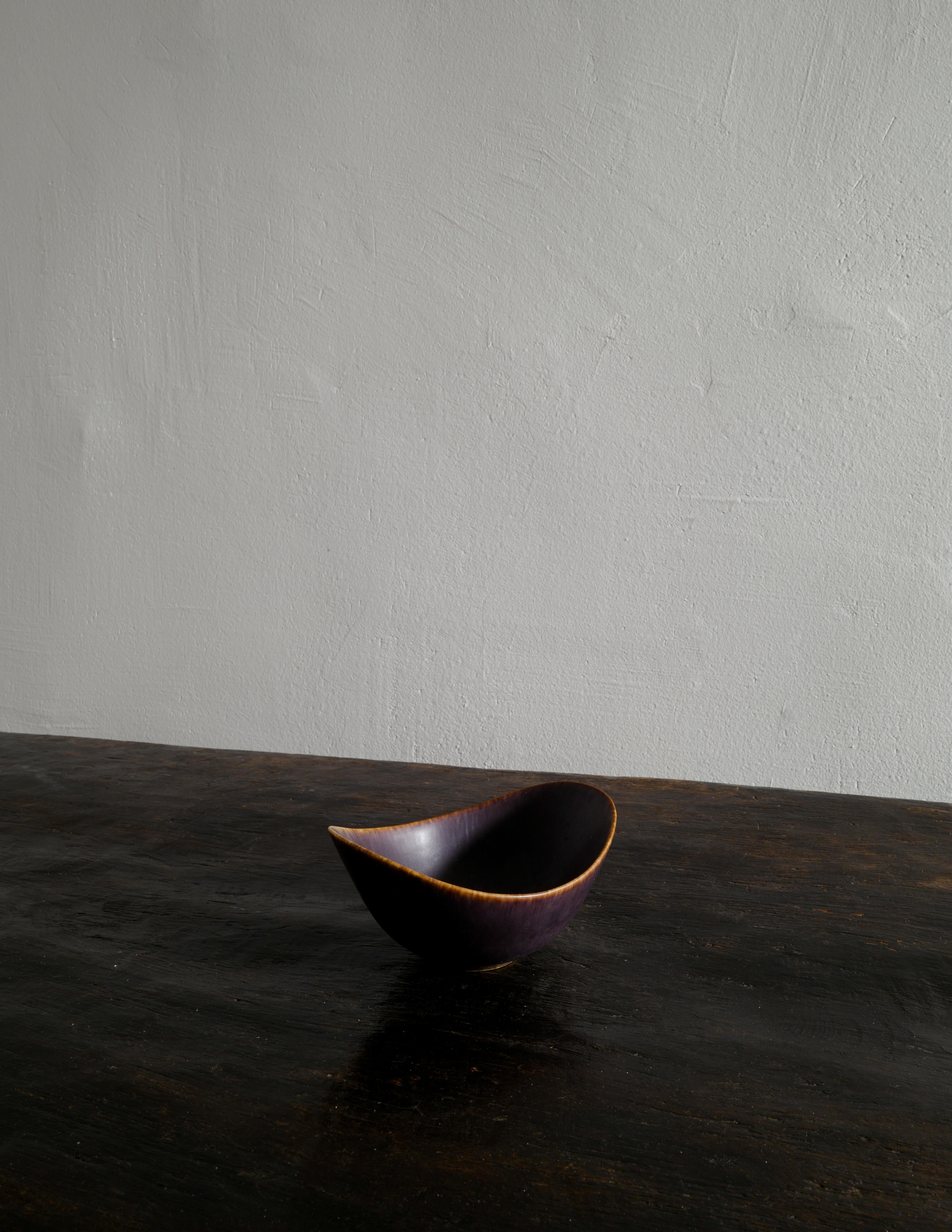 Rare and beautiful bowl by Gunnar Nylund in a mostly dark brown glaze with some blue spots produced by Rörstrand, Sweden in the 1950s. In good vintage condition with small signs from age and use. Signed.

Dimensions: H: 8 cm W: 16 cm D: 12 cm.