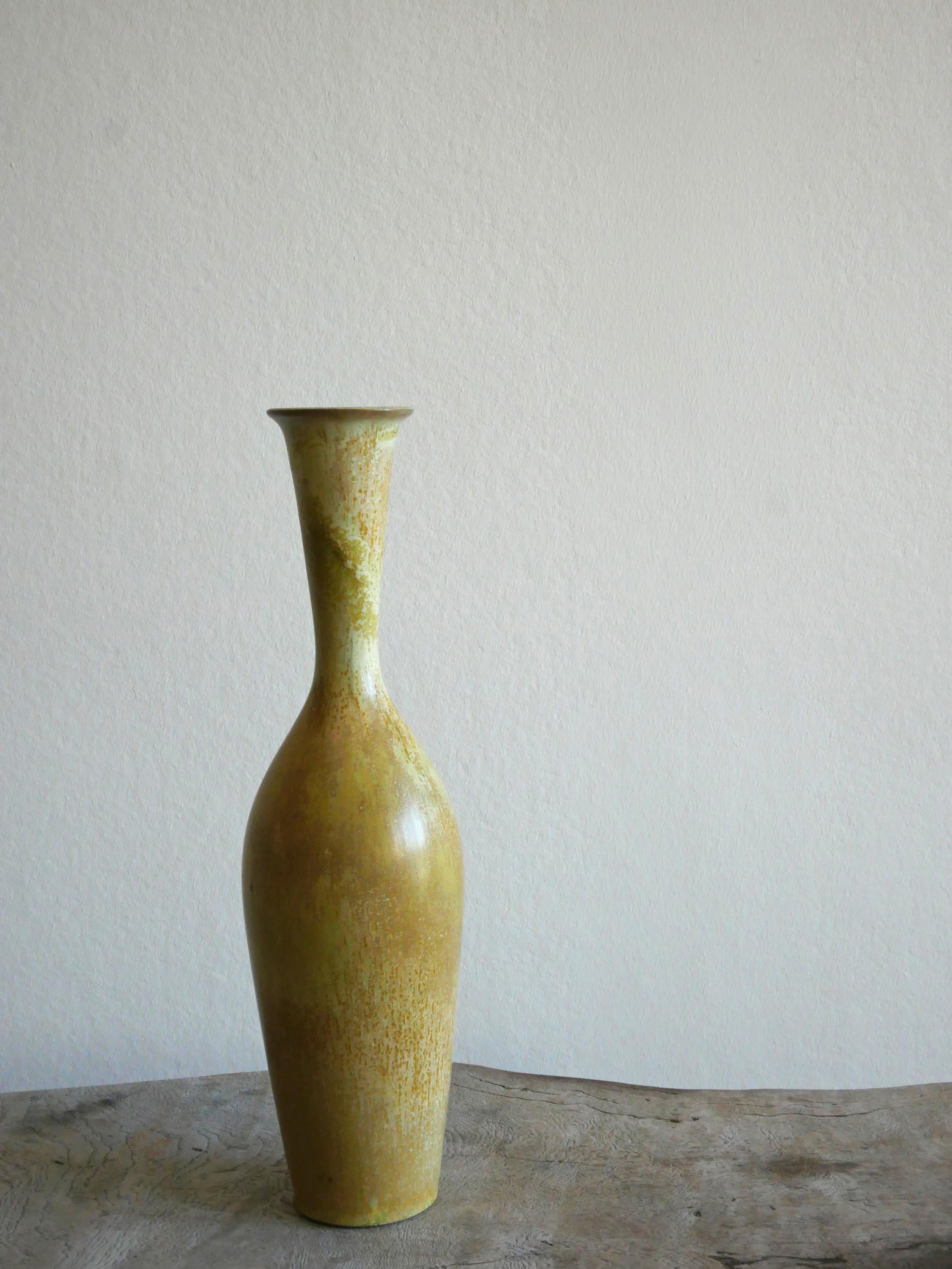 Diese wunderbare Vase wurde von Gunnar Nylund in der Rörstrand Fabrik in den 1950er Jahren in Schweden entworfen und hergestellt.

Die Glasur in grünen und gelben Farben ist erstaunlich und passt wunderbar zu der flaschenhalsförmigen Vasenform.

Die