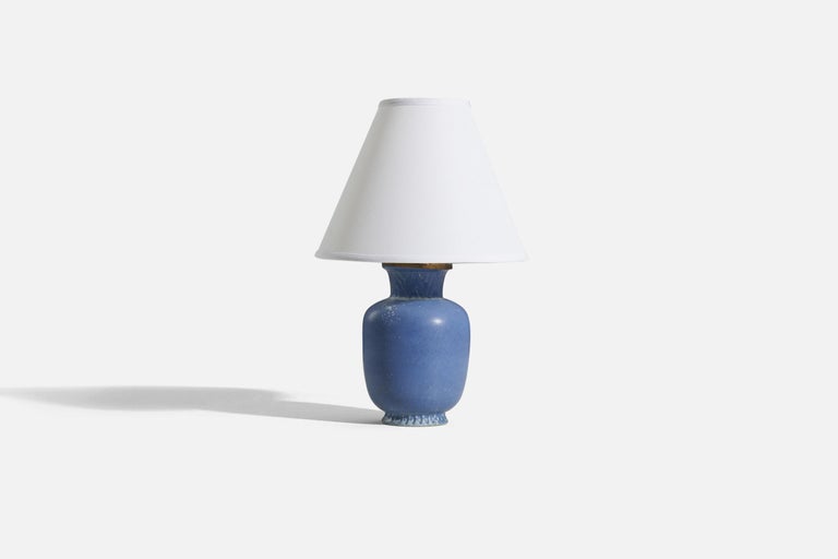 A blue-glazed stoneware and brass table lamp, designed by Gunnar Nylund and produced by Rörstrand, Sweden, 1950s.

Sold without lampshade. 
Dimensions of Lamp (inches) : 11.1875 x 5 x 5 (H x W x D)
Dimensions of Shade (inches) : 4 x 10 x 8 (T x