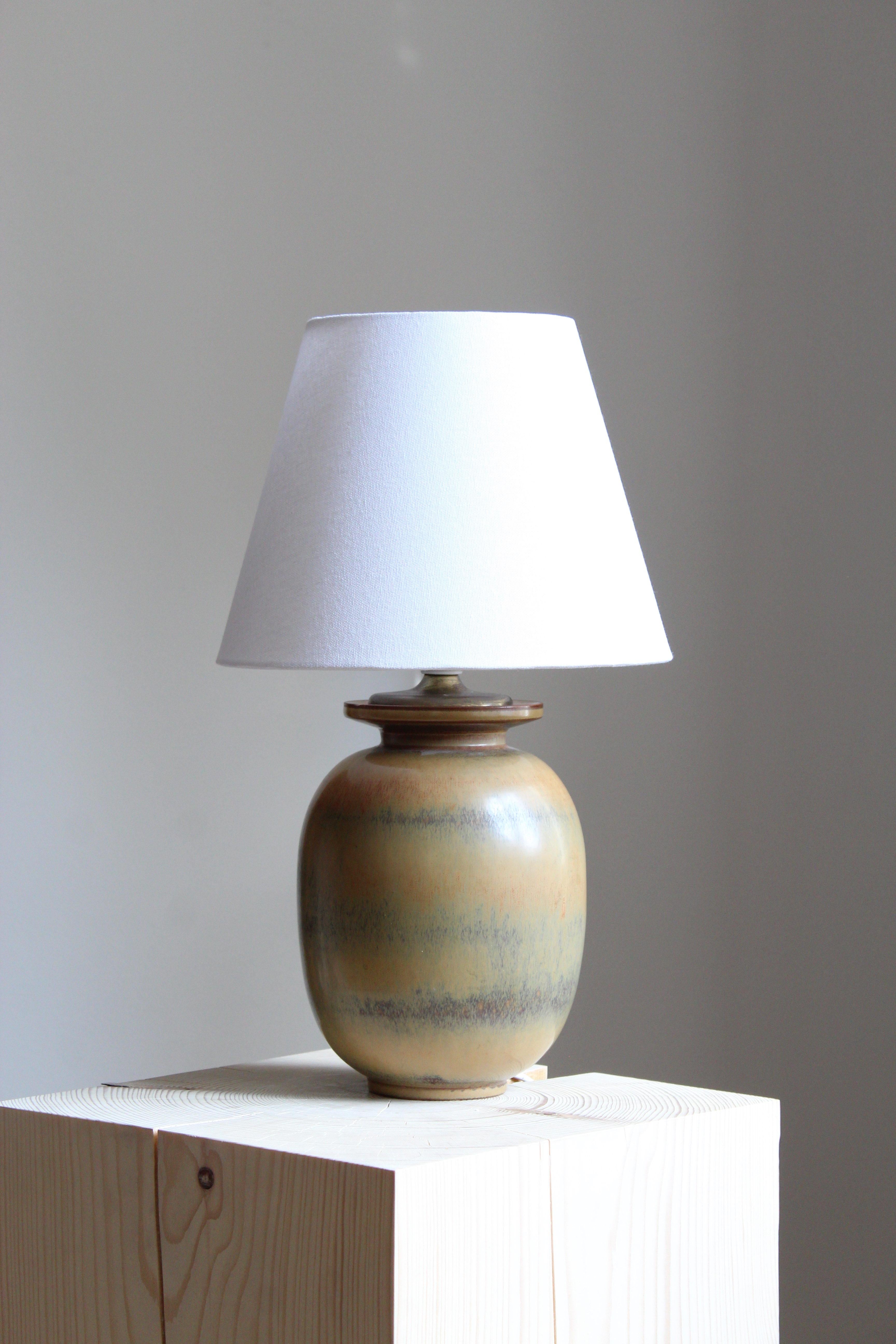 A table lamp produced by Rörstrand, Sweden, 1940s. Designed and signed by Gunnar Nylund, (Swedish, 1914-1997). Factory second

Nylund served as artistic director at Rörstrand, where he worked, 1931-1955. Prior to his work at Rörstrand he was a