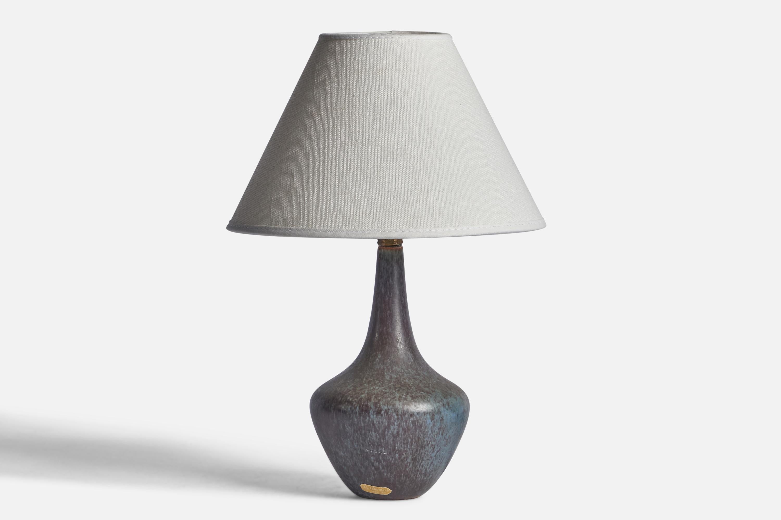 A blue-glazed stoneware table lamp designed by Gunnar Nylund and produced by Rörstrand, Sweden, 1940s.

Dimensions of Lamp (inches): 8.75” H x 4” Diameter
Dimensions of Shade (inches): 3” Top Diameter x 8” Bottom Diameter x 5” H 
Dimensions of Lamp