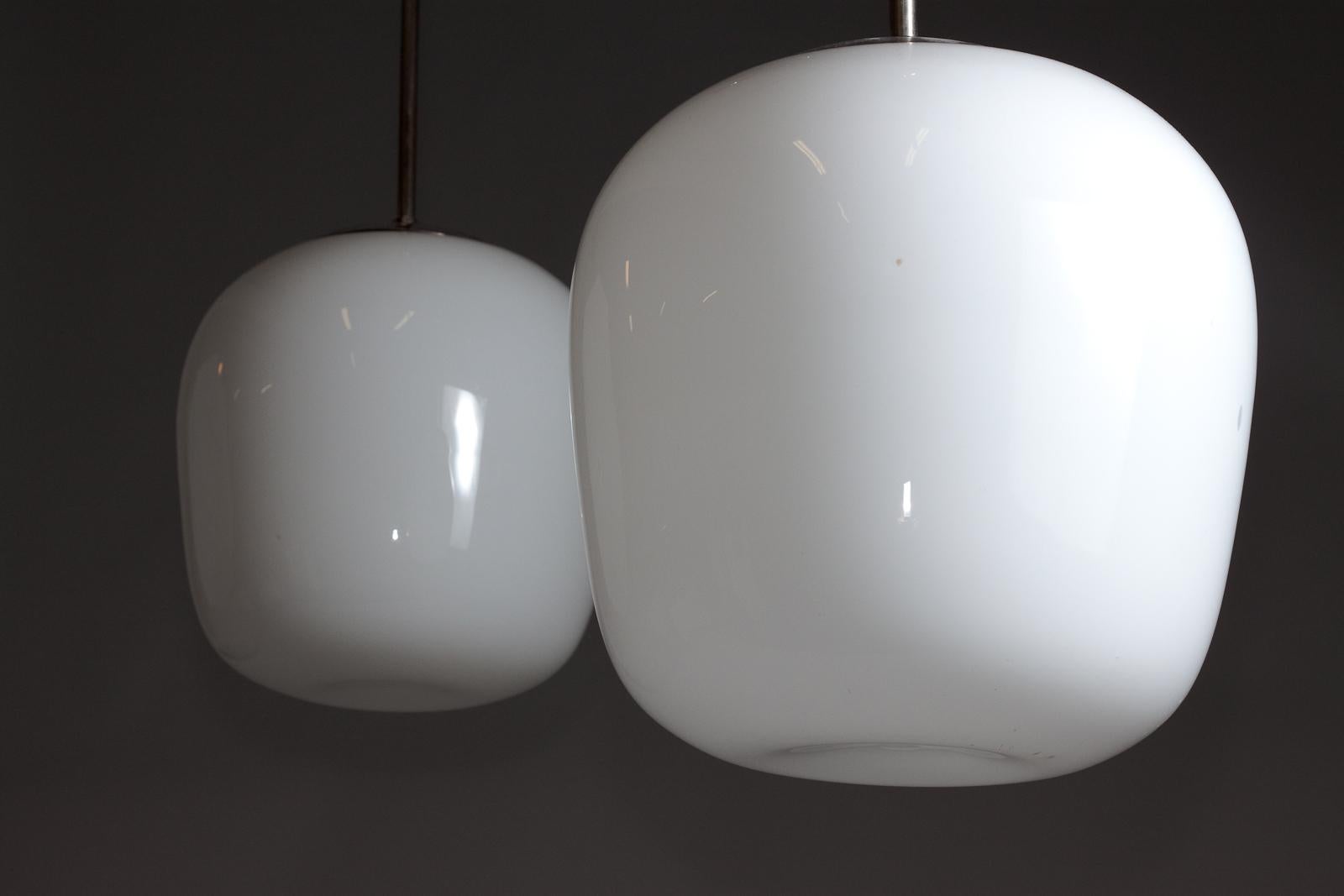 Introducing the exquisite Gunnel Nyman pair of 1940s opaline glass pendant lamps, crafted for Idman Oy. These vintage pendant lamps feature a visually stunning opaline glass diffuser, providing a soft, warm glow that enhances any interior space. The
