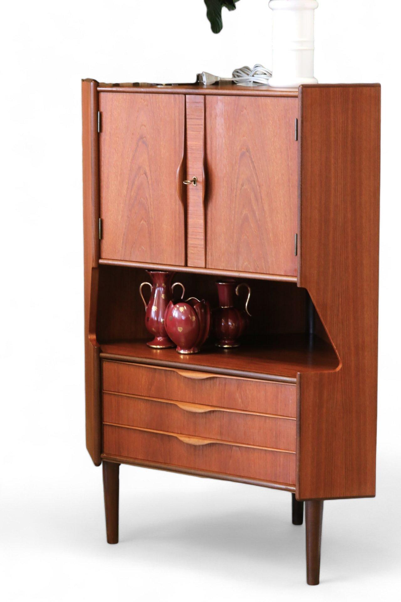 
Un mueble esquinero/barra de impresionante belleza diseñado por Gunni Oman para Oman Jun en Dinamarca. Los muebles son de teca con un tono marrón dorado y un veteado mágico en toda la superficie. El armario tiene un mueble bar en la parte superior