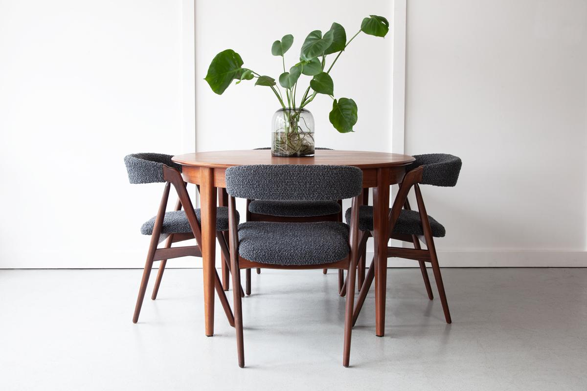 An extendable dining table in teak, designed by Gunni Omann for Omann Jun Møbelfabrik. A single separate leaf slots in to extend the table to a larger oval size. Standing on elegantly tapering legs, this dining table is a wonderful example of paired