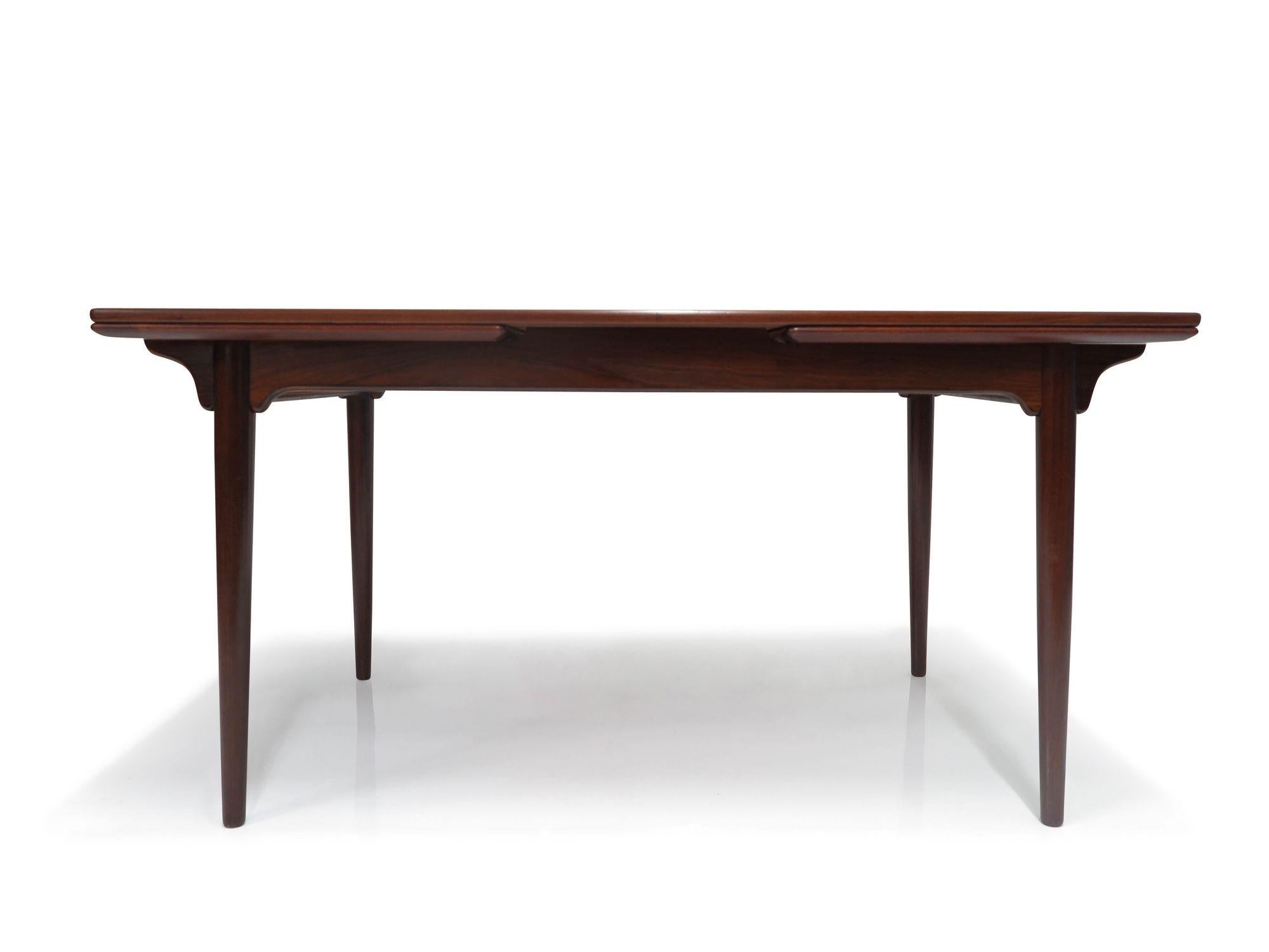Danish Rosewood dining table, designed by Gunni Omann for Omann Jun Mobelfabrik, circa 1960, Denmark, Model 54. This table boasts a stunning book-matched grain on the top surface, edged in solid rosewood. It comfortably seats six when closed and